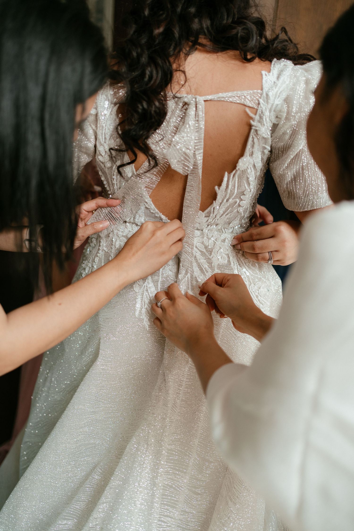 A bride having her dress fastened during wedding morning preparations in Portugal