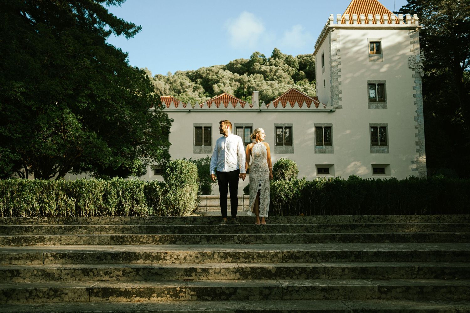 A couple standing together on the stone steps of a grand manor house during their elopement in Portugal