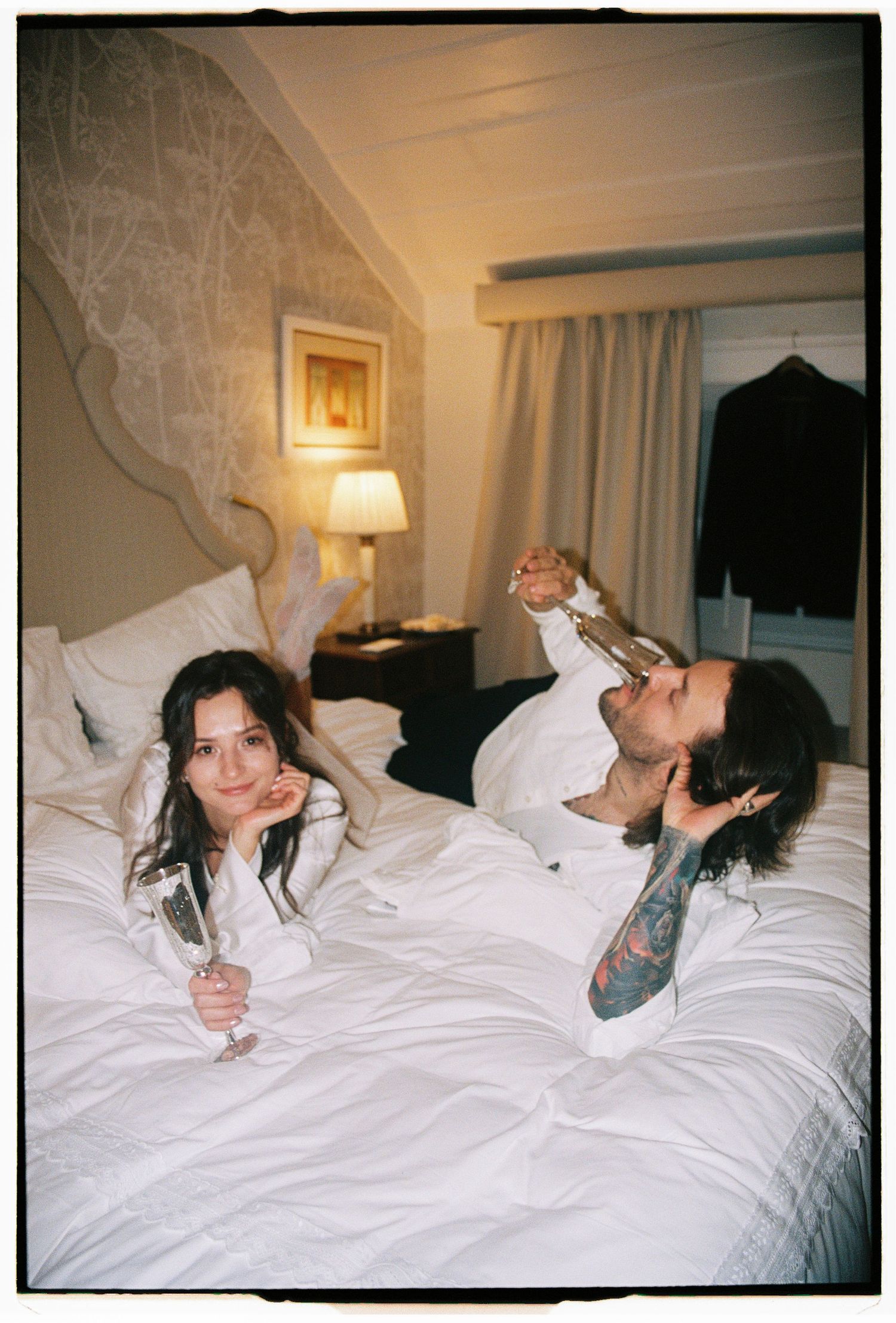 Bride and groom laughing on hotel bed after intimate elopement, documentary wedding photographer Lisbon