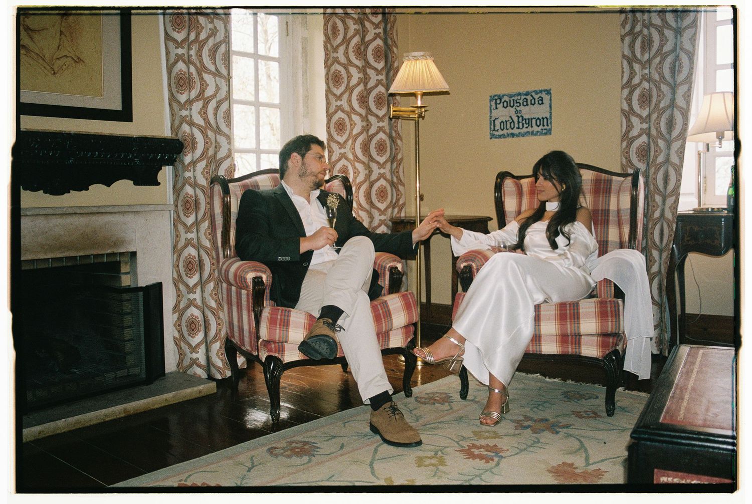 A film photograph of a couple sitting together in a warmly lit vintage living room during their elopement at Lawrence's Hotel in Sintra