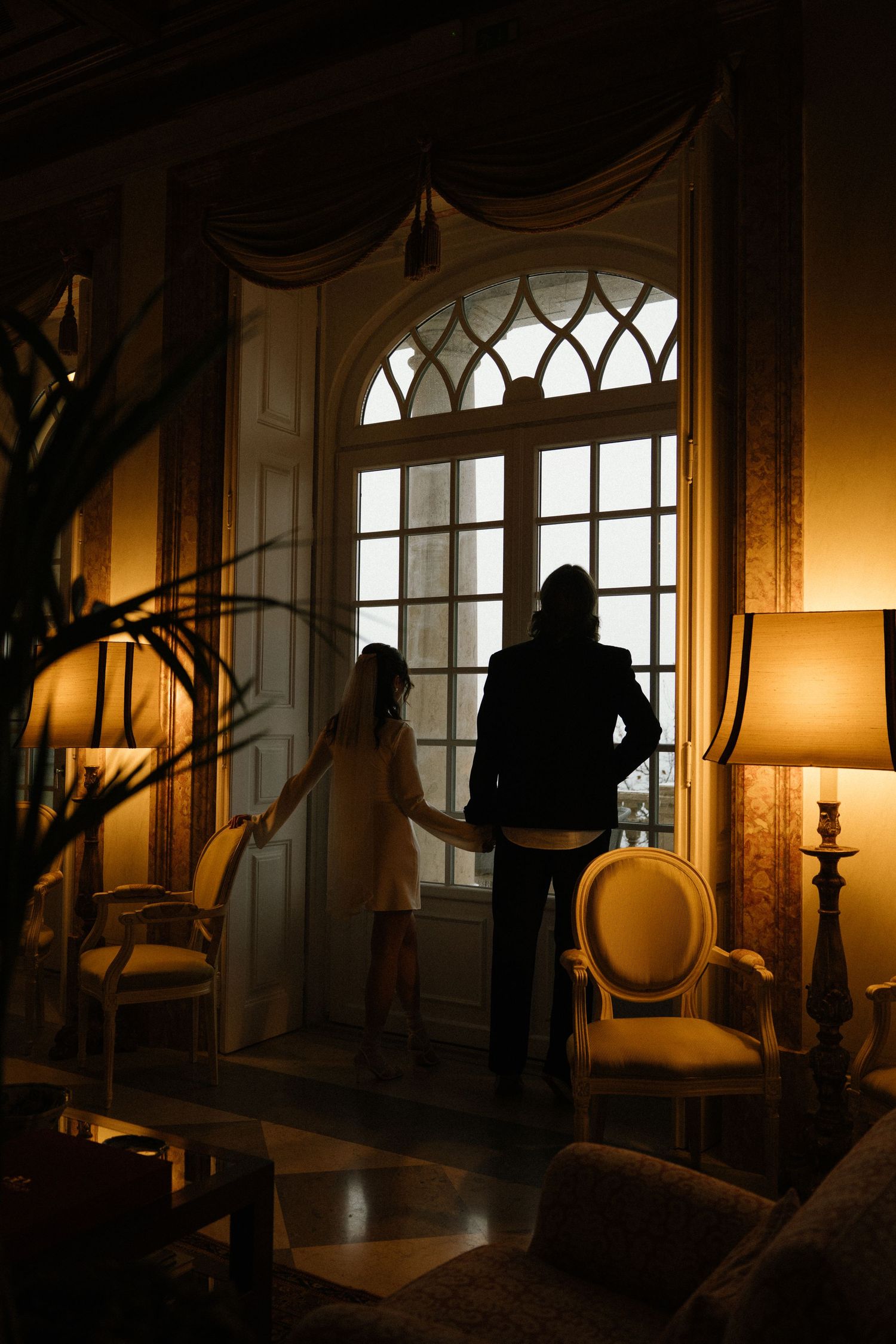 Bride and groom silhouetted by window in ornate hotel interior, intimate elopement Estoril Vintage Hotel Lisbon