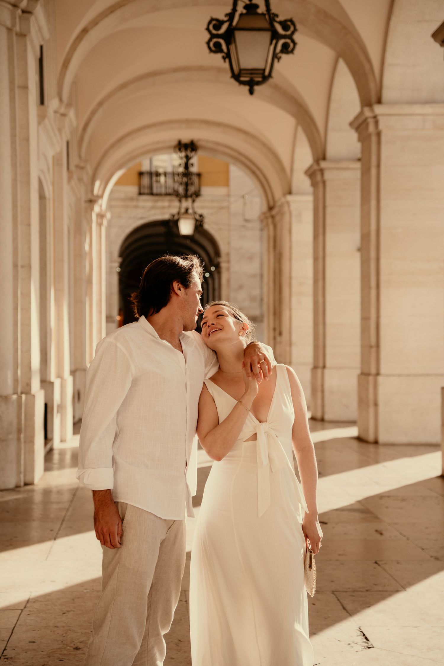 A couple embracing in a sunlit arched colonnade in Lisbon during a couples photography session in Portugal