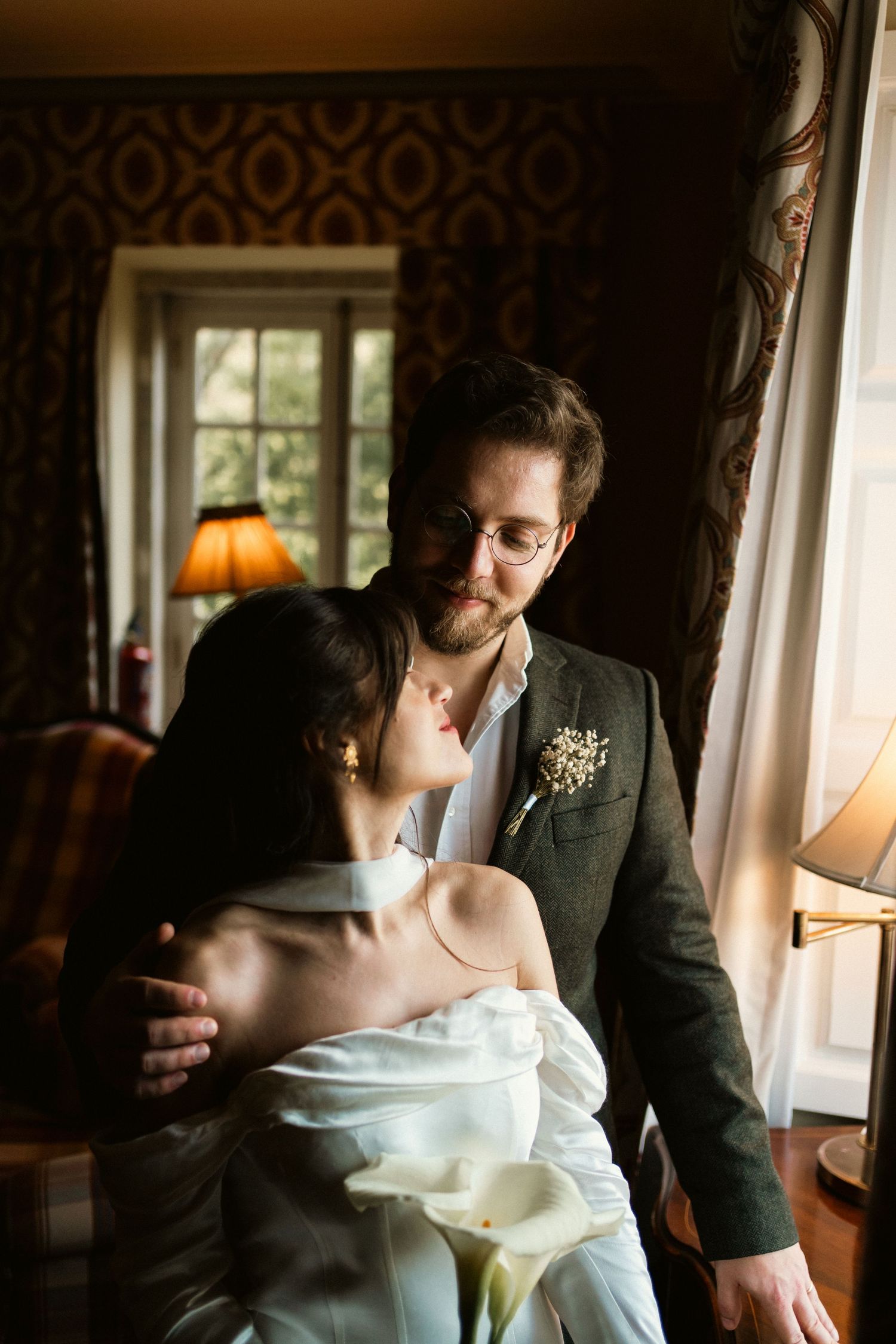 A couple sharing a tender moment by a window in a warmly lit room during their elopement in Sintra
