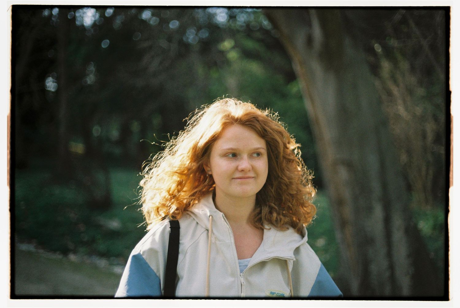 A portrait of photographer Polina Hedzenko in a lush green garden in Lisbon, Portugal