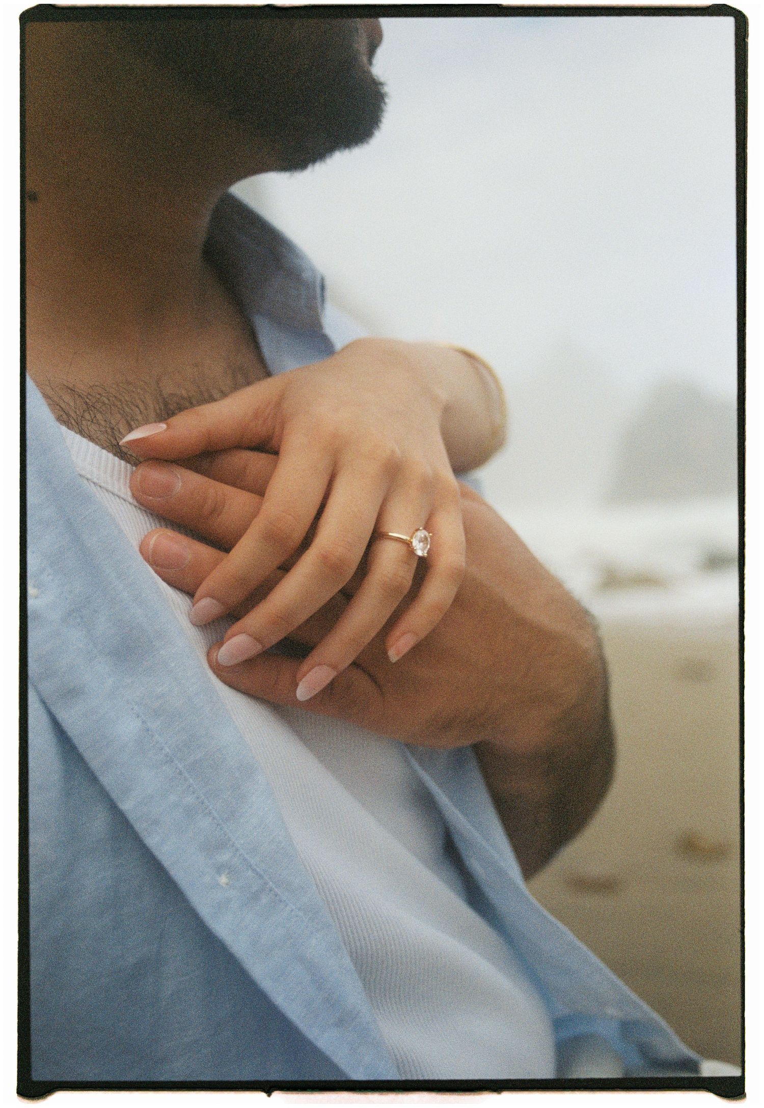 A film close-up of a couple holding hands with a wedding ring on a beach in Portugal