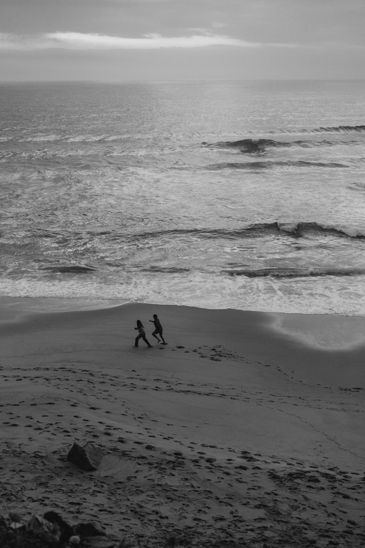 A couple walking together along a wide beach in Portugal during a couples photography session