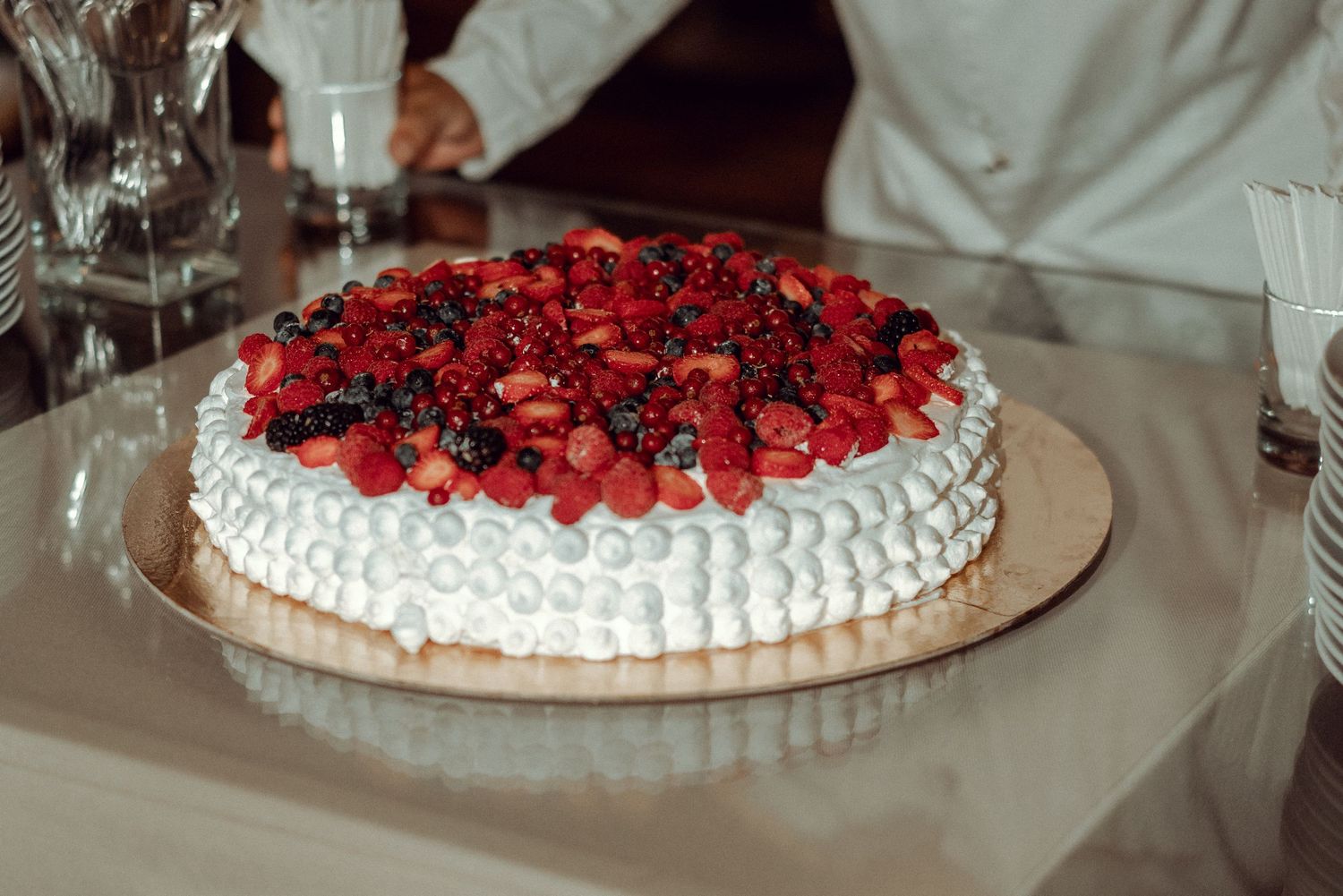 A white wedding cake topped with fresh strawberries and berries at a wedding reception in Portugal
