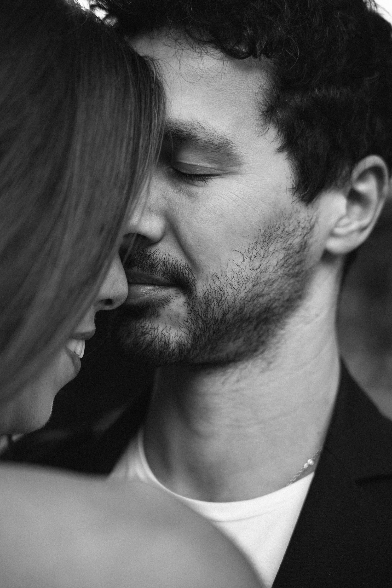 A black and white close-up portrait of a couple sharing a tender moment during a pre-wedding session in Lisbon, Portugal