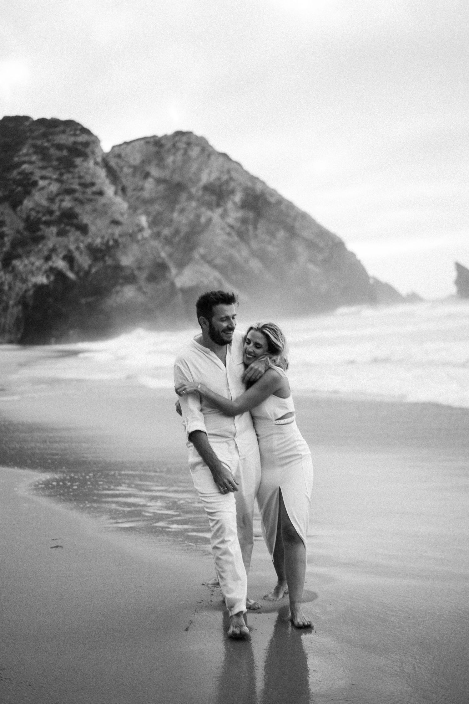 A couple playing in the waves on Praia da Adraga during their wedding portraits session in Portugal