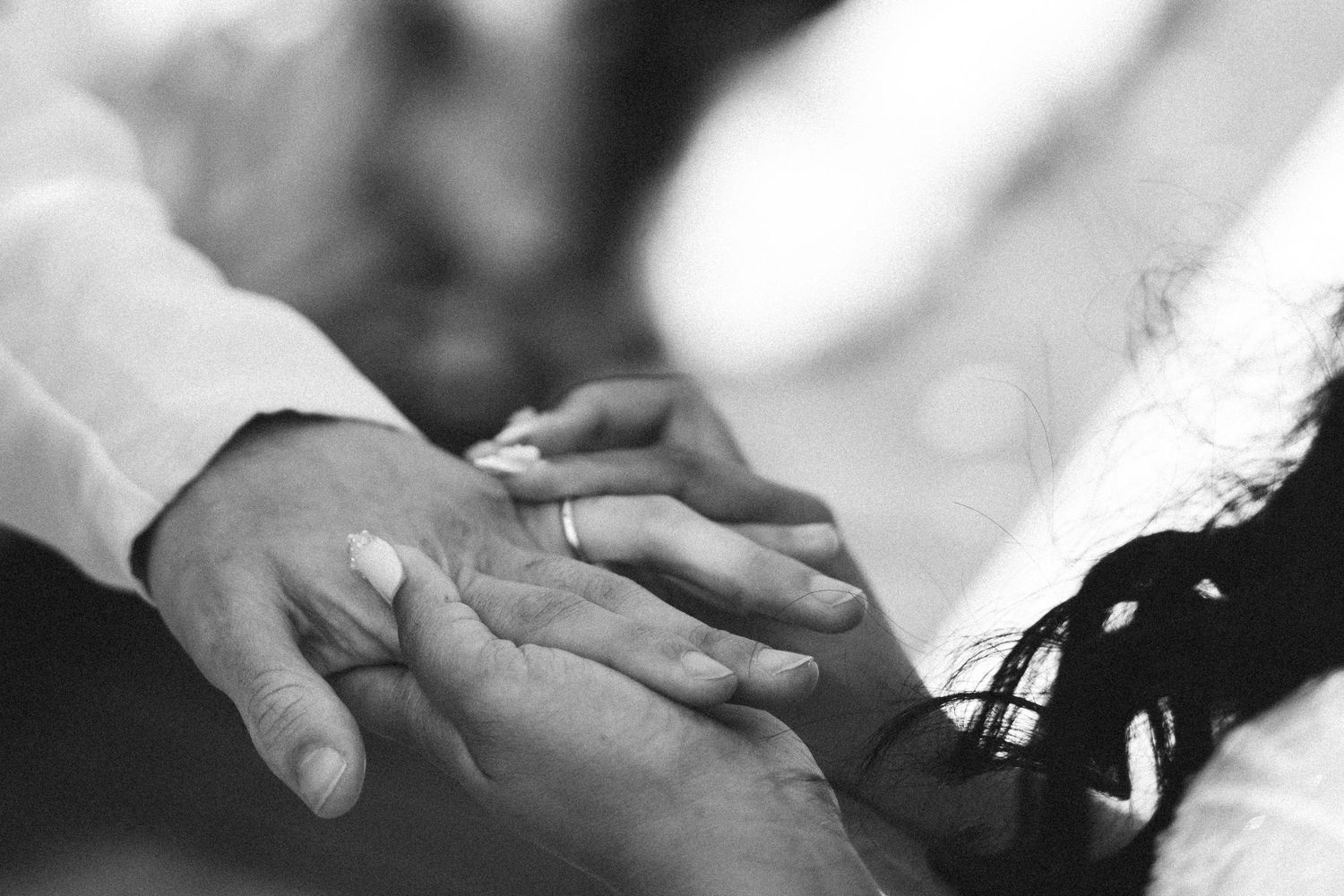 Black and white close-up of hands gently touching in an intimate moment during wedding ceremony in Portugal
