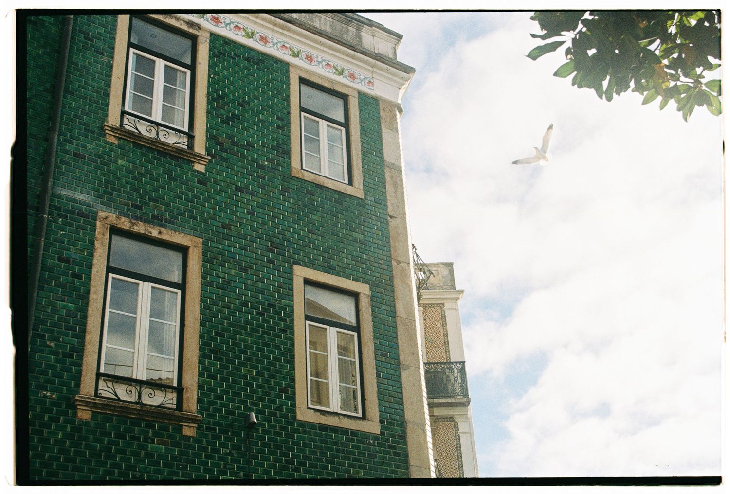 A film photograph looking up at a traditional green tiled building in Lisbon, Portugal