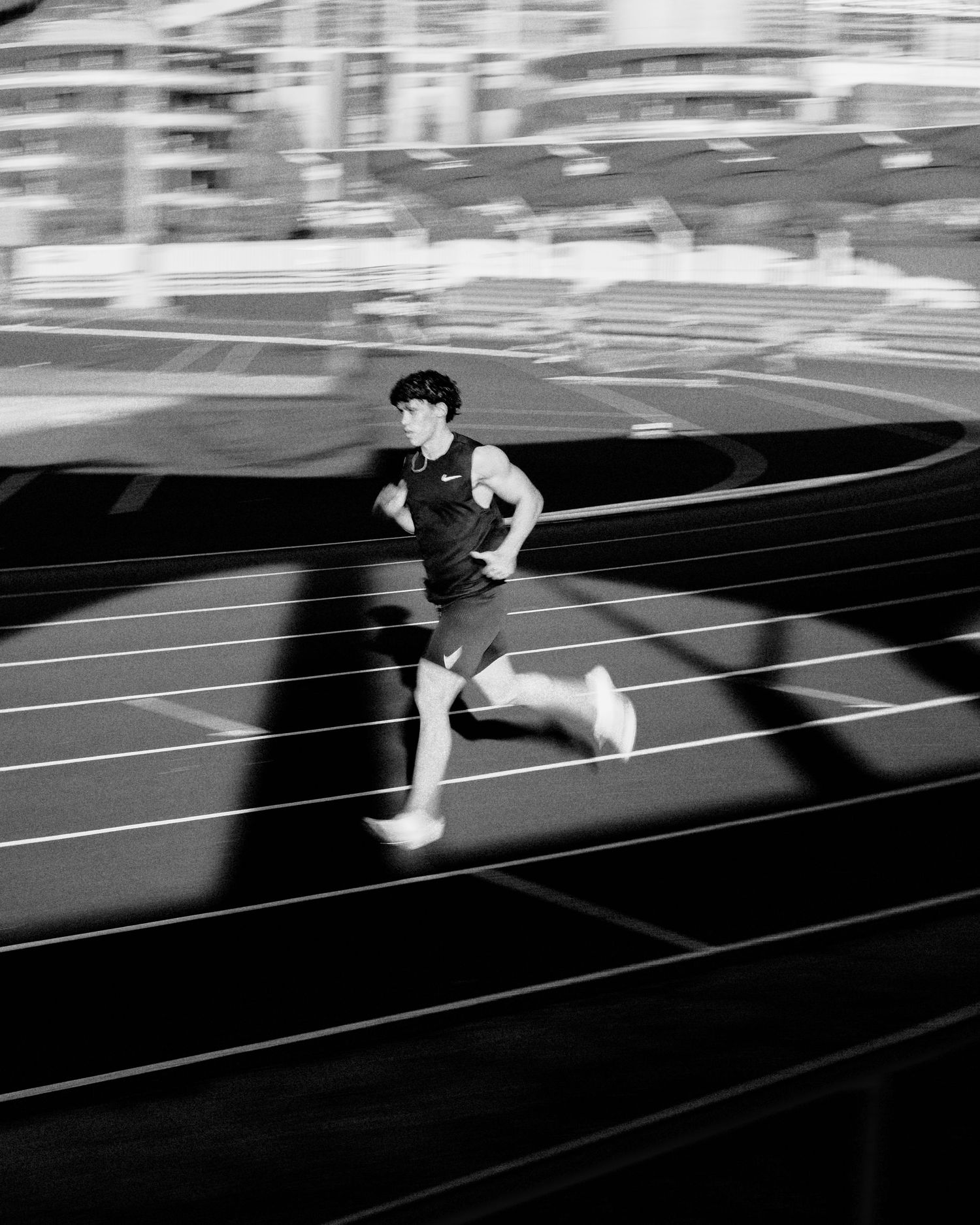 High contrast black and white photo of runner sprinting on athletic track.