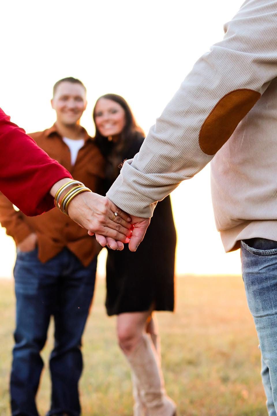 Married couple holding hands walking towards other couple.