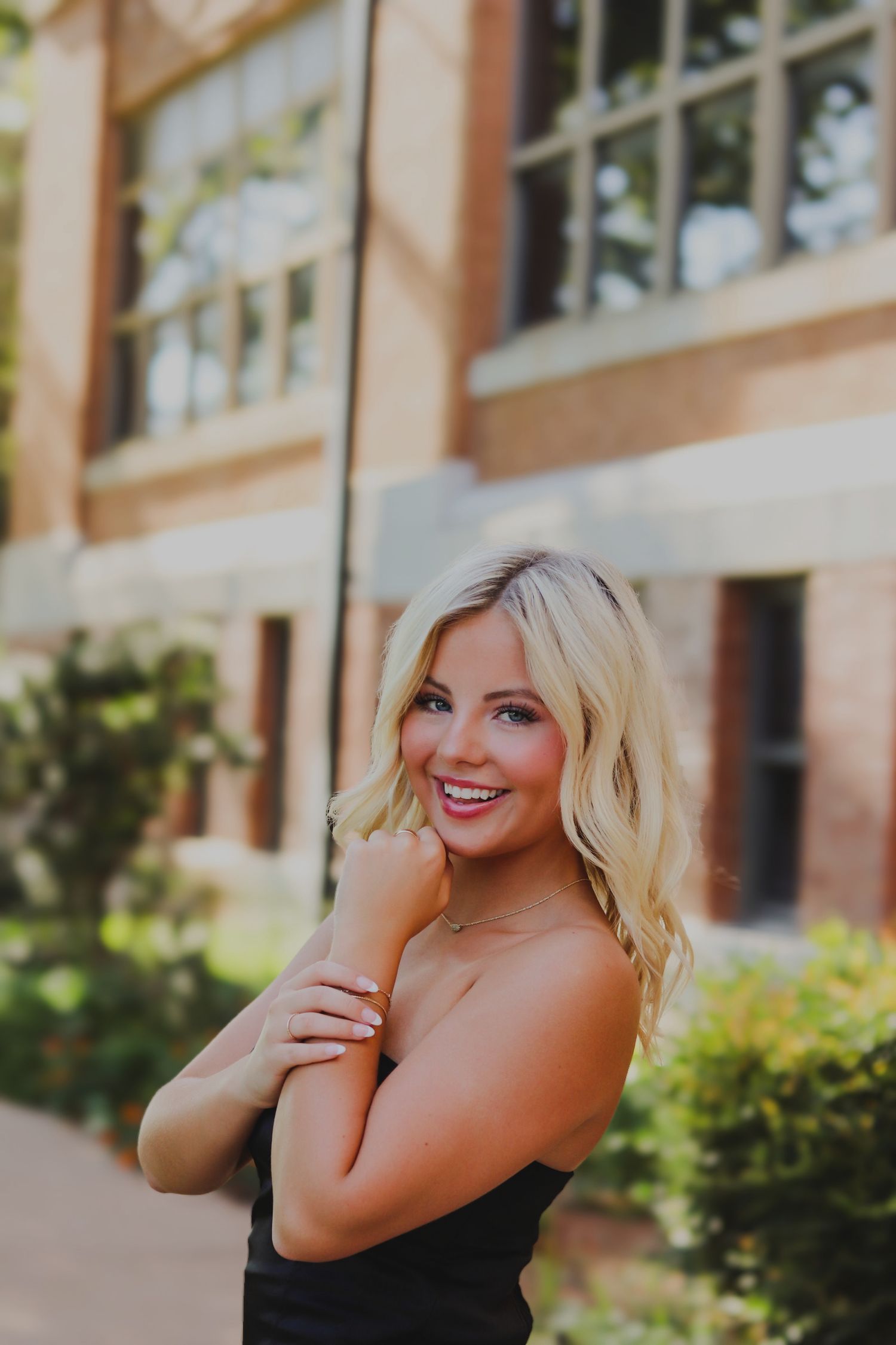 Senior picture of a blonde girl standing by a building.