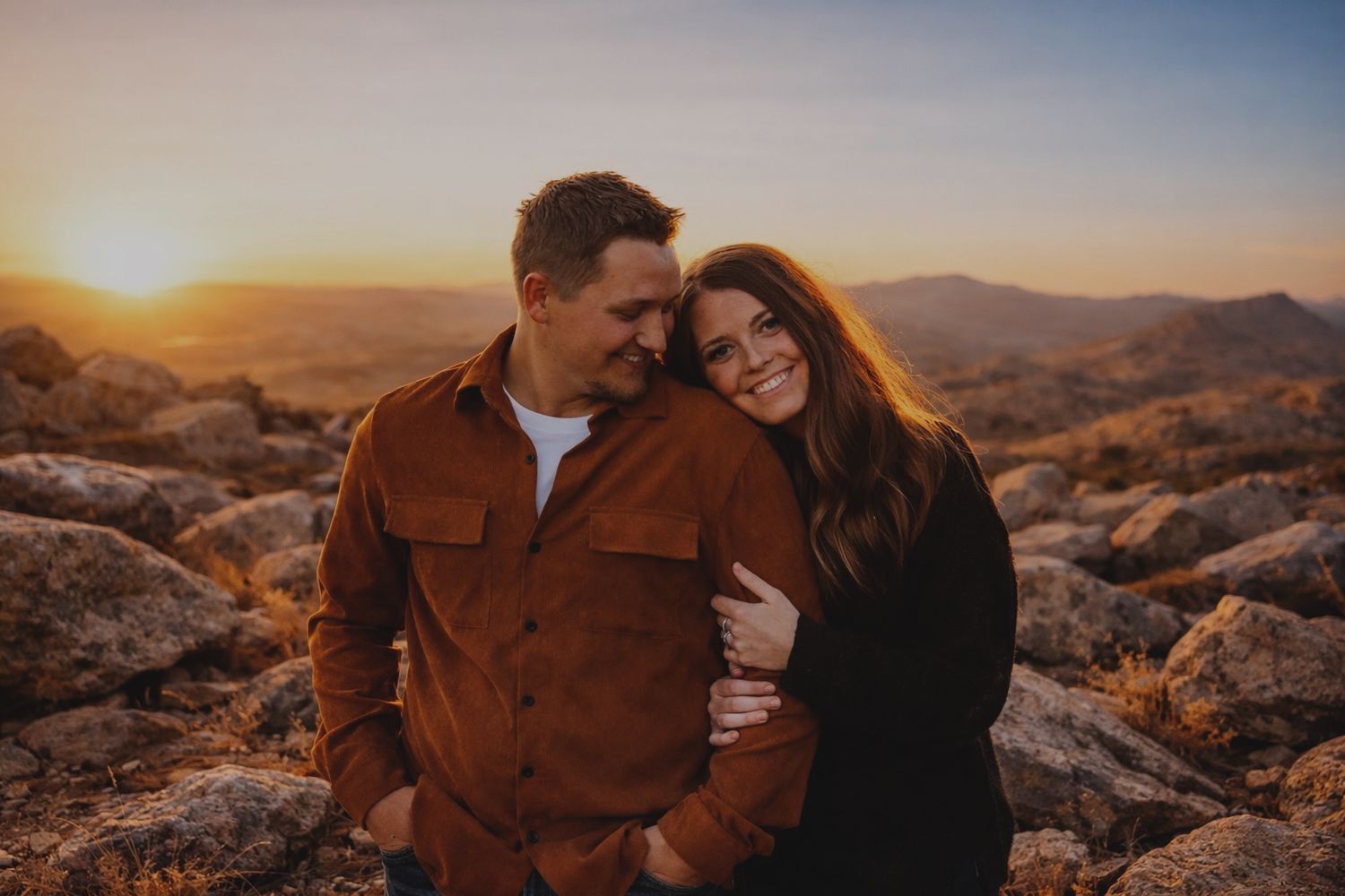 Married couple setting out on the horizon by a field with rocks.