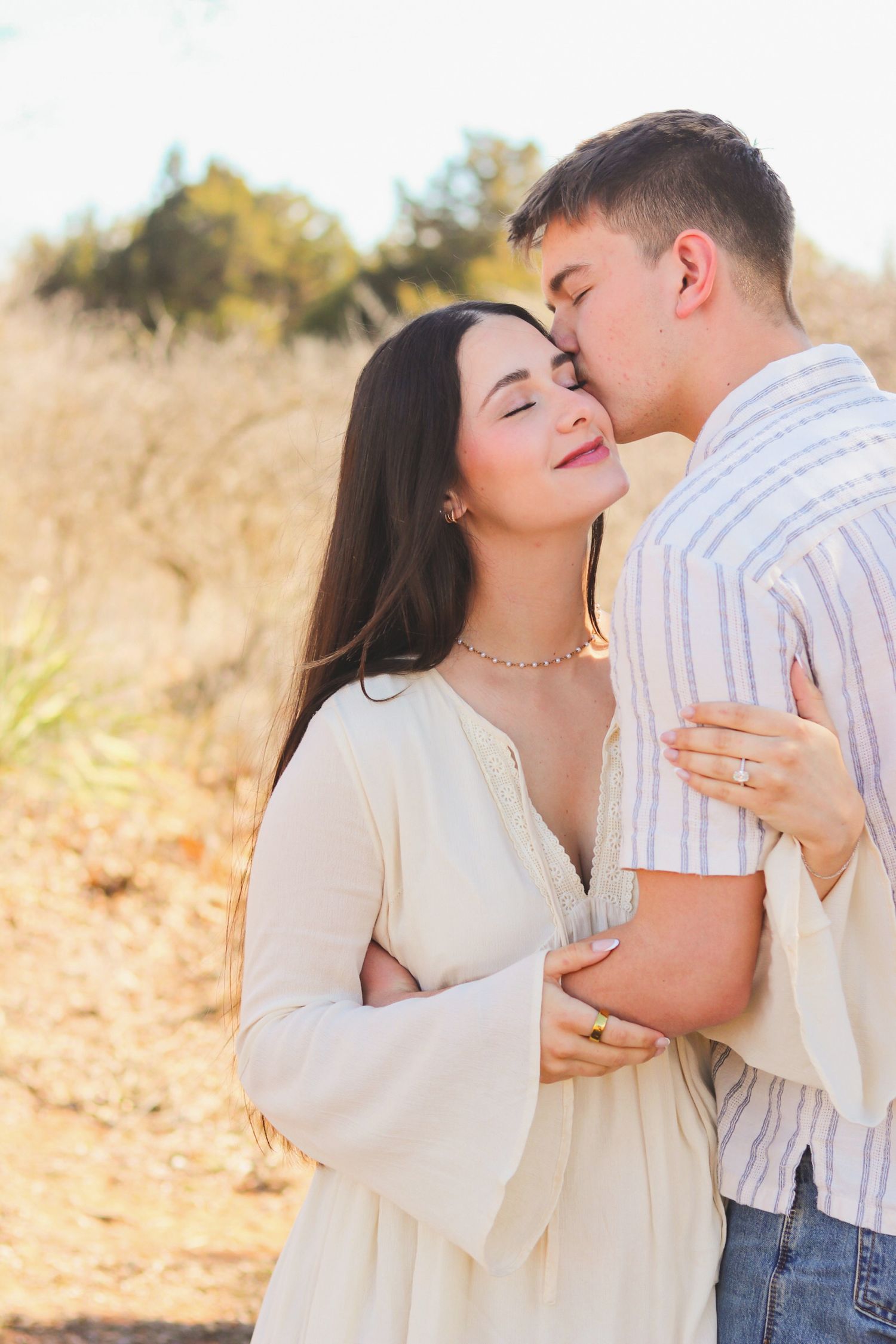 An engaged couple kissing.