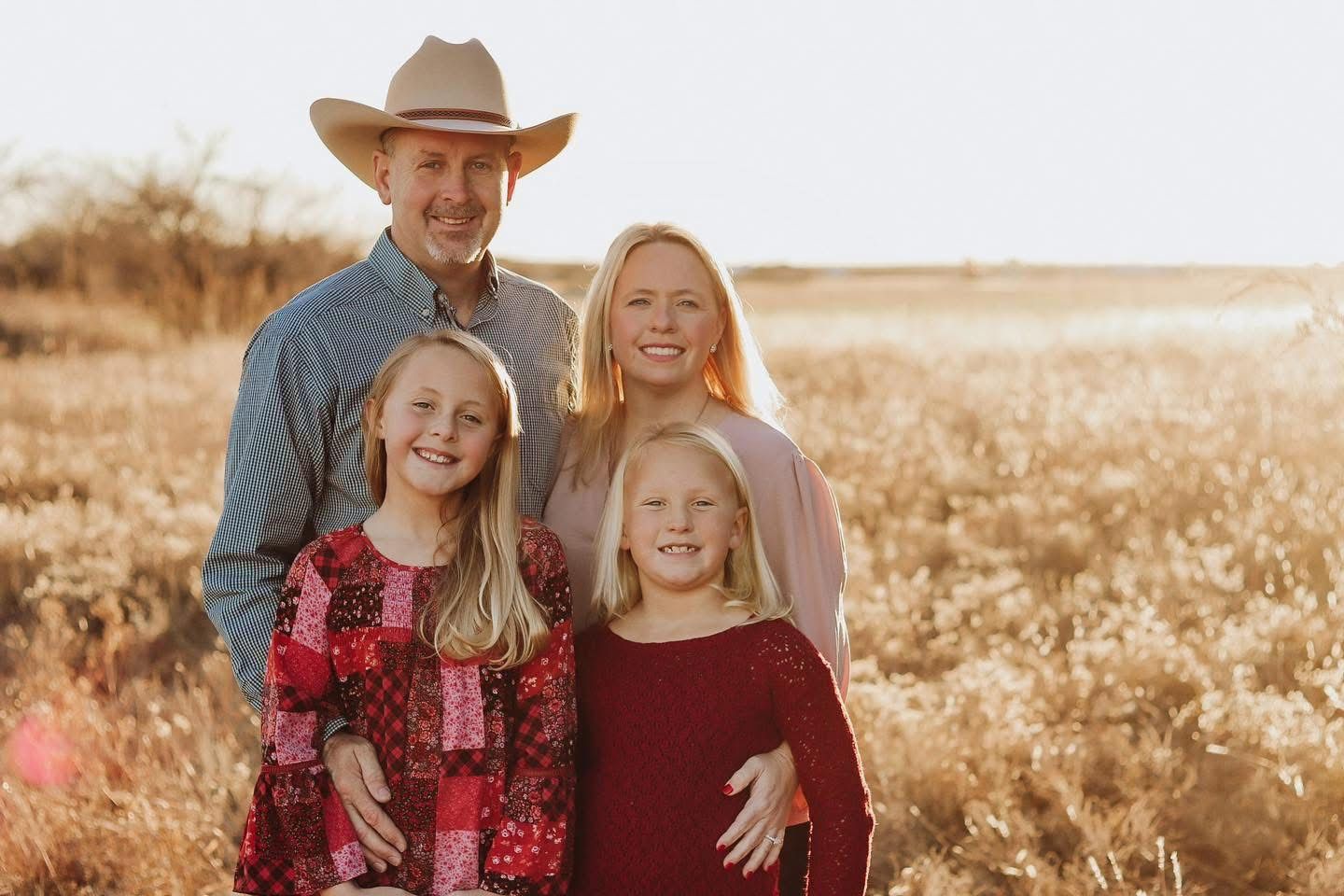 Family of four standing in a field by the country side.