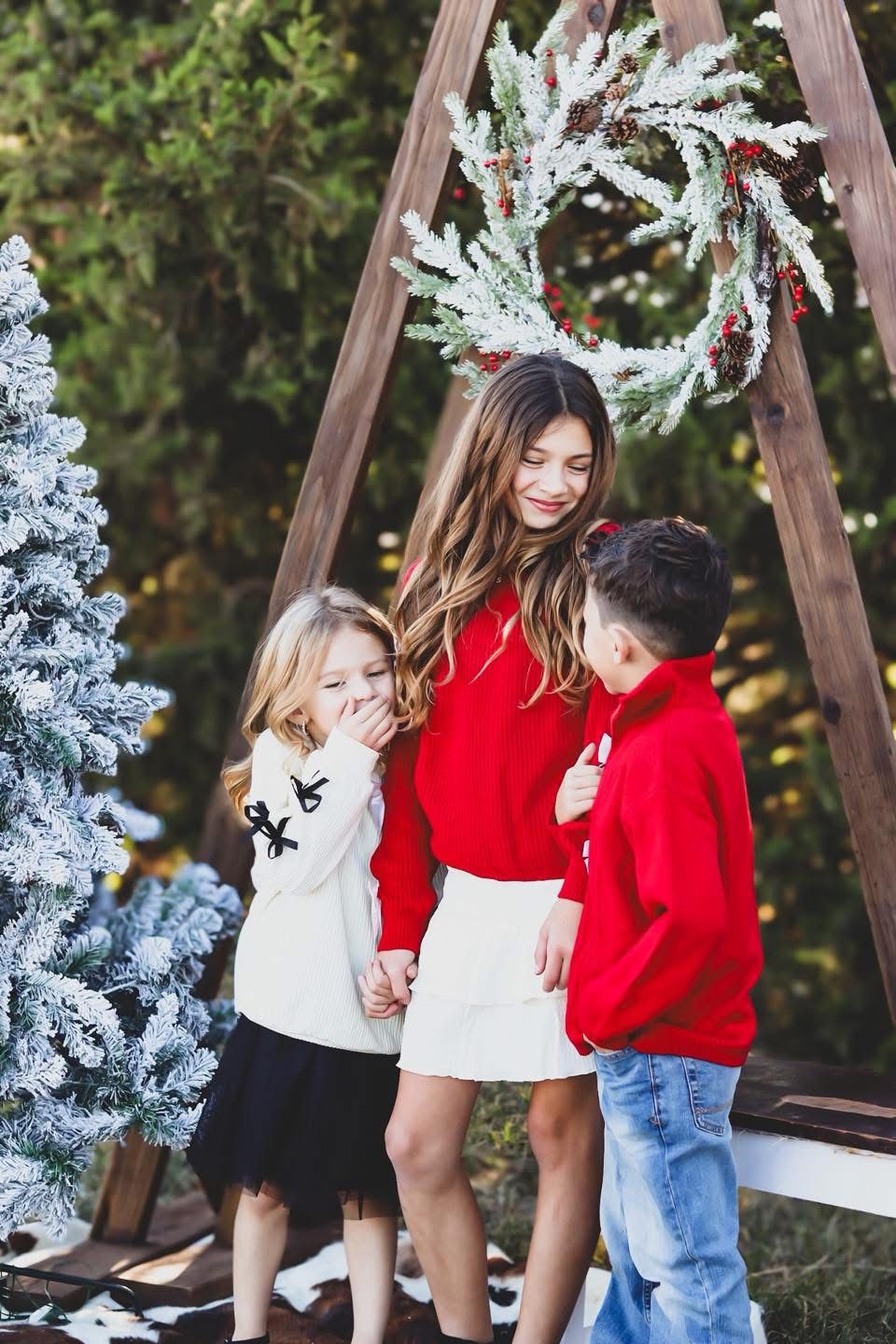 Young siblings laughing under a wreath.