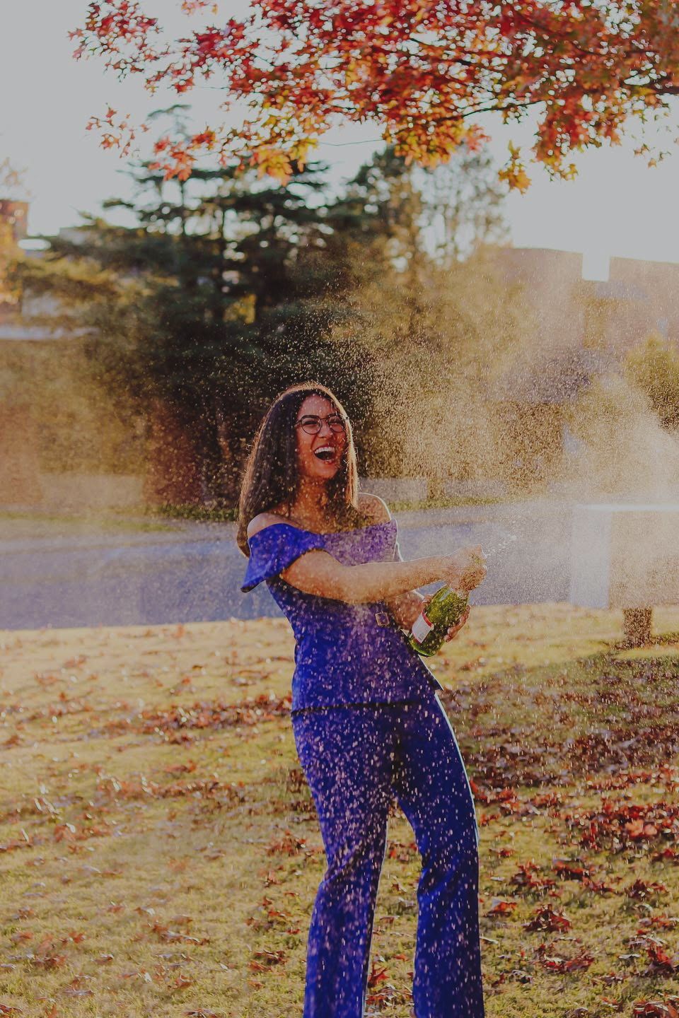 A college graduate celebrating by popping a bottle of champagne.