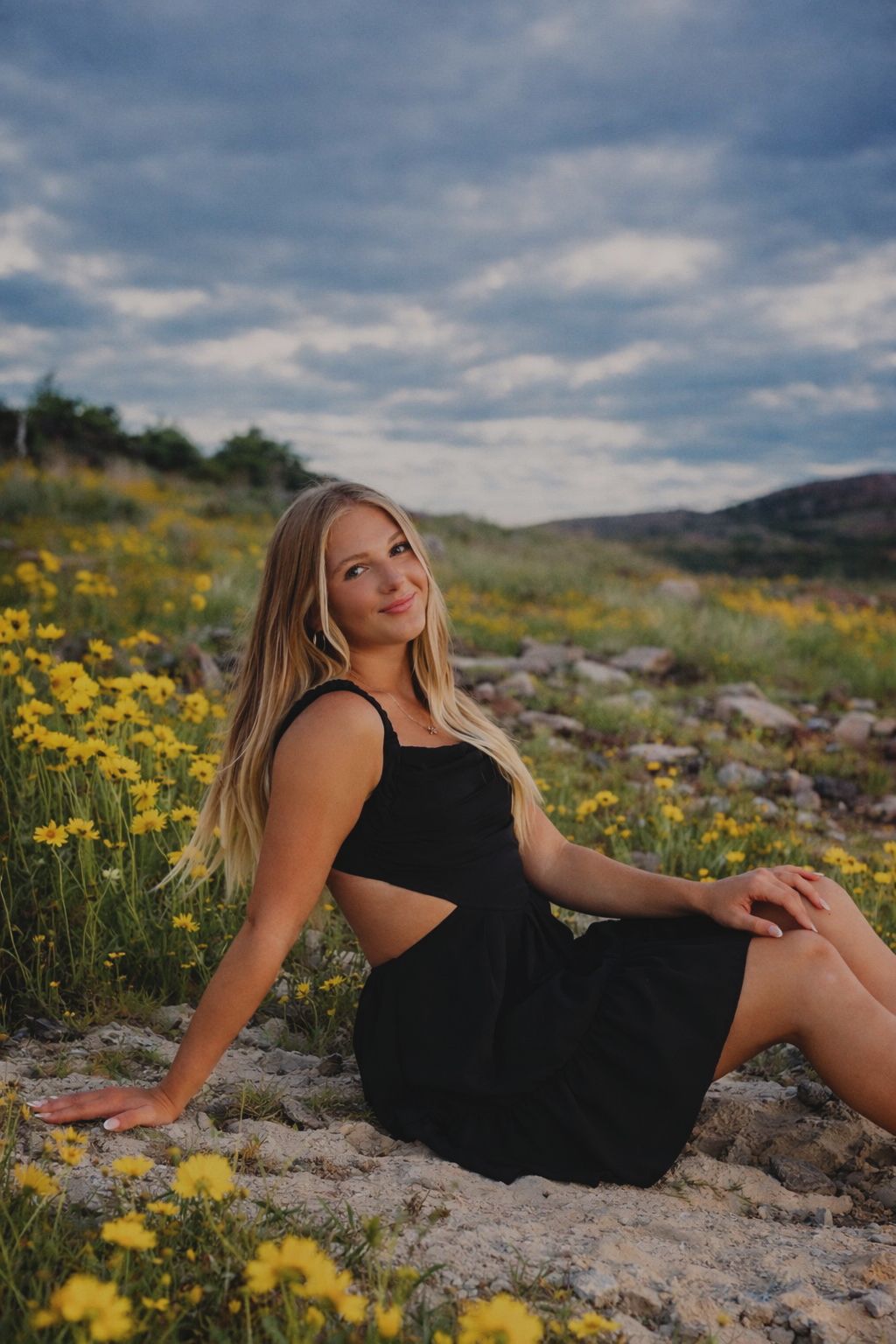 Blonde senior graduate posing in a field of flowers.