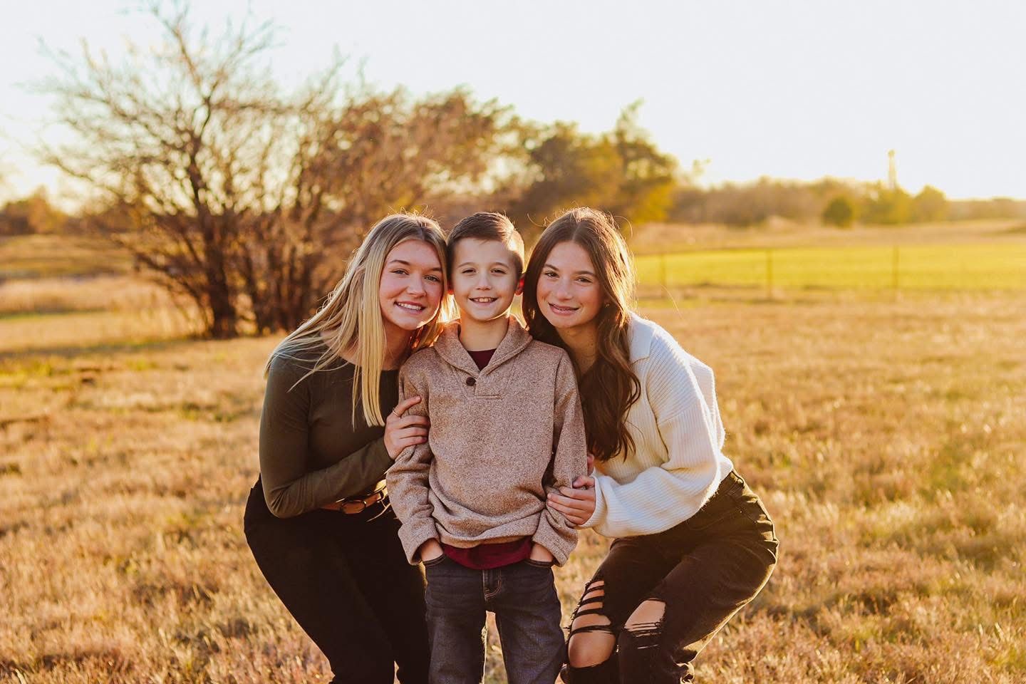 Siblings posed in a field.