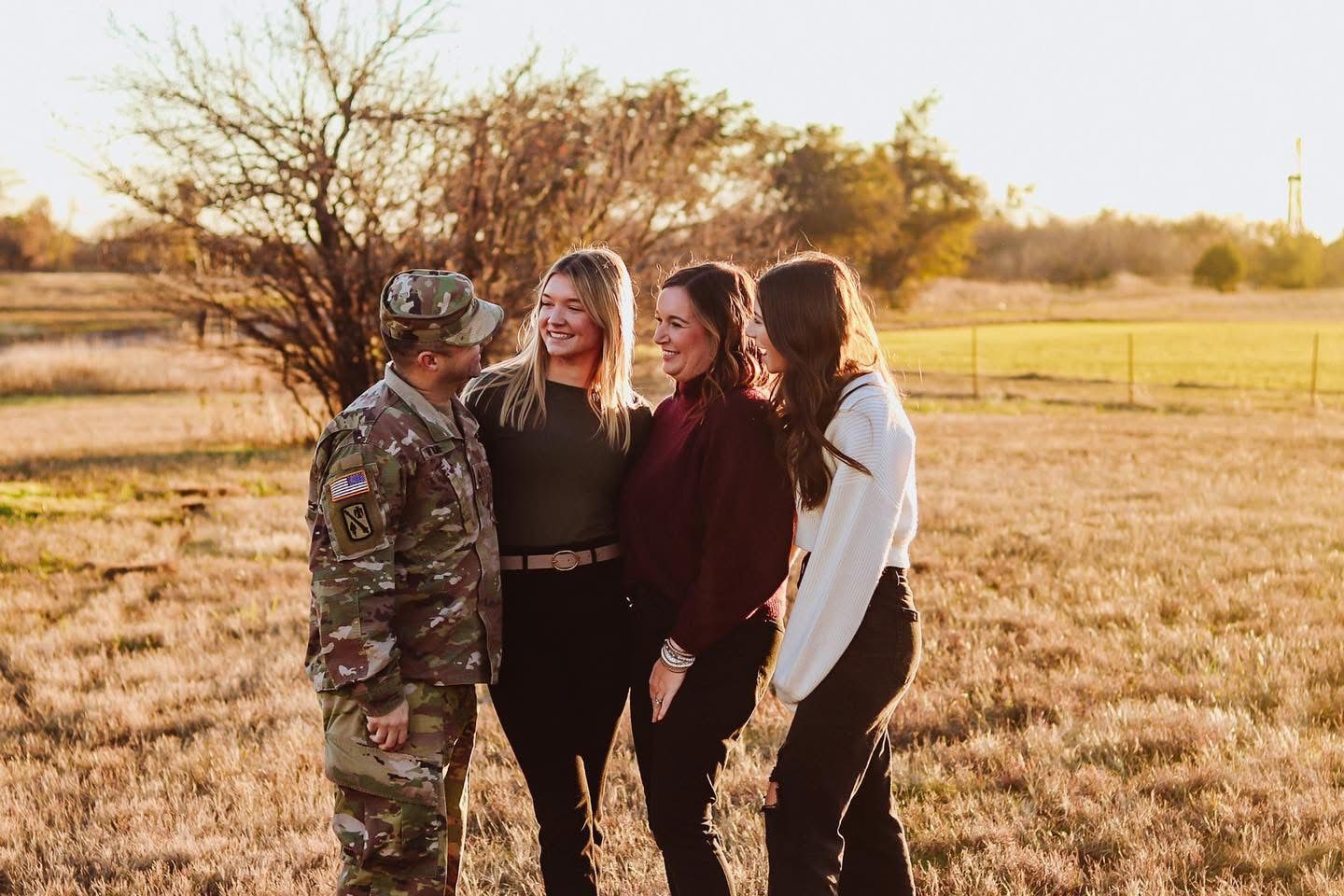 Family surprised by military father in a field.