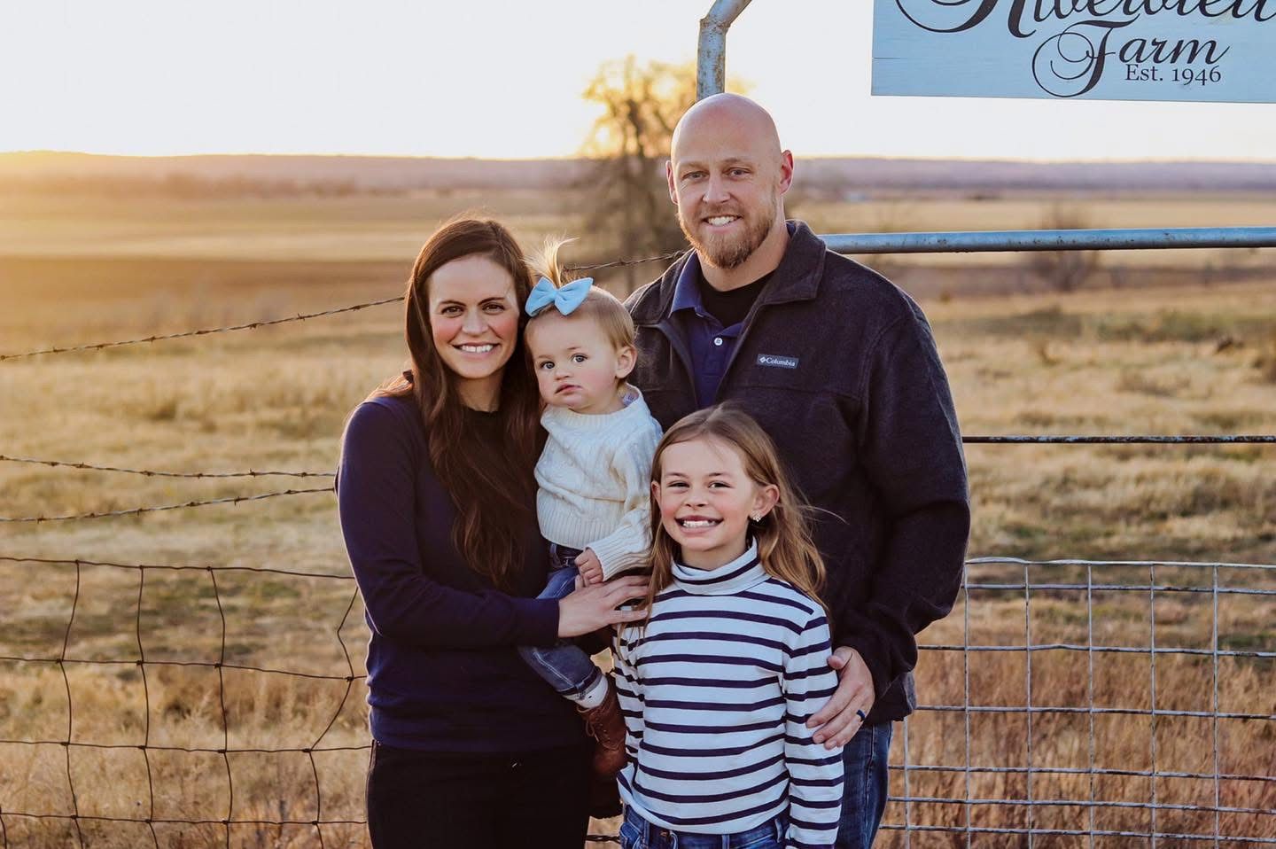 Family by a farm sign with their name on it.