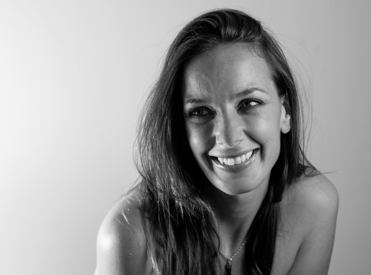 Black and white studio portrait of a smiling young woman with long hair.