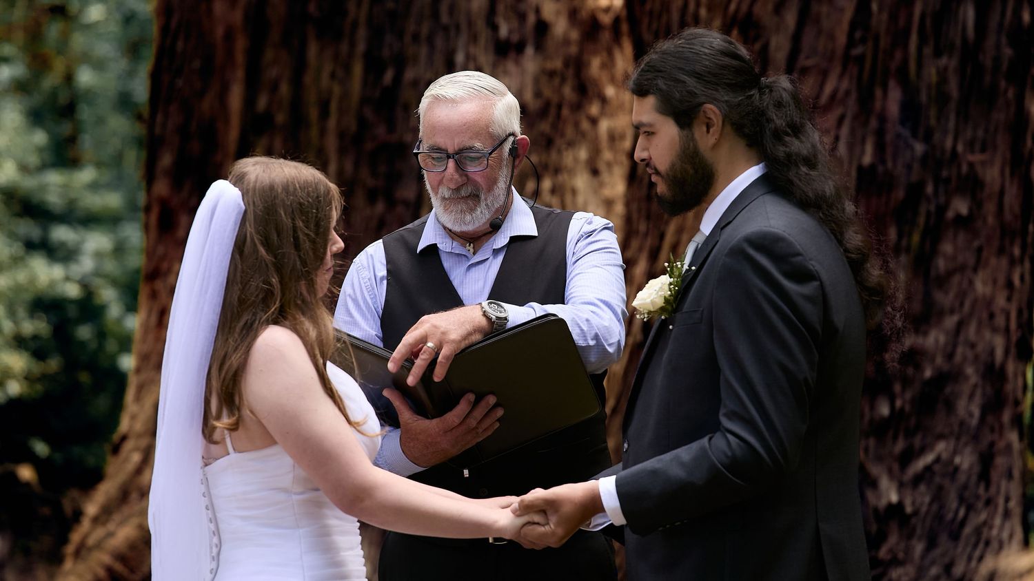 Couple exchanging vows with officiant during intimate forest wedding ceremony.
