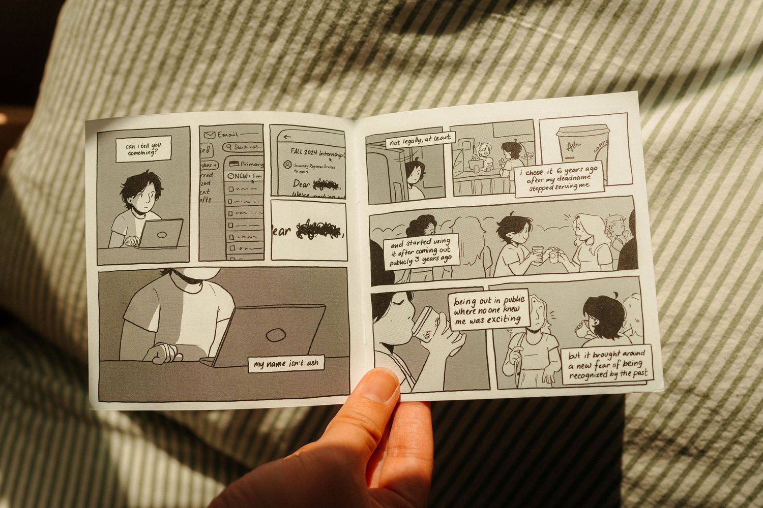 Ash Does Comics holding open a black and white comic book with illustrated panels.