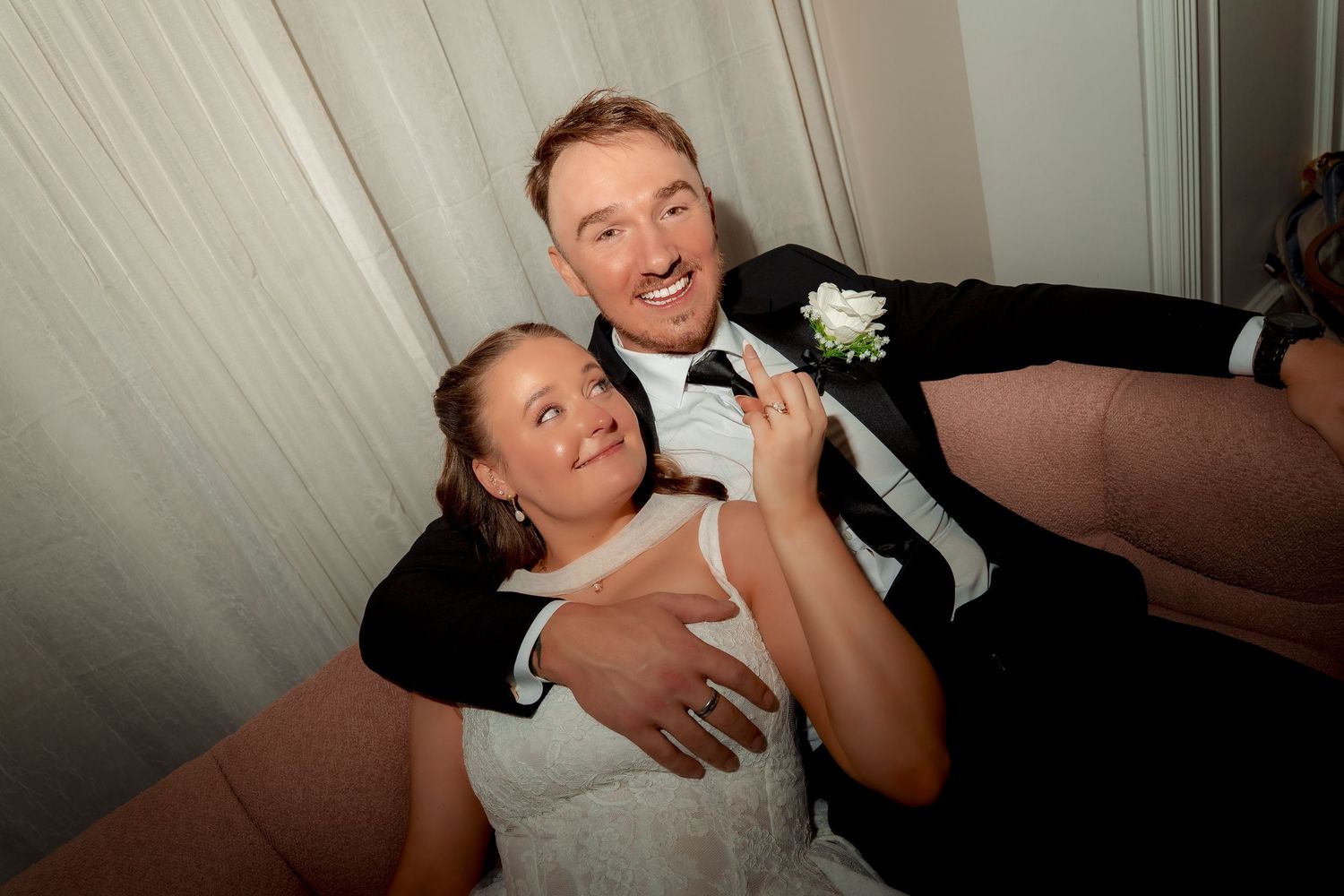 Joyful bride and groom strike a fun playful pose together at their wedding reception photo booth.