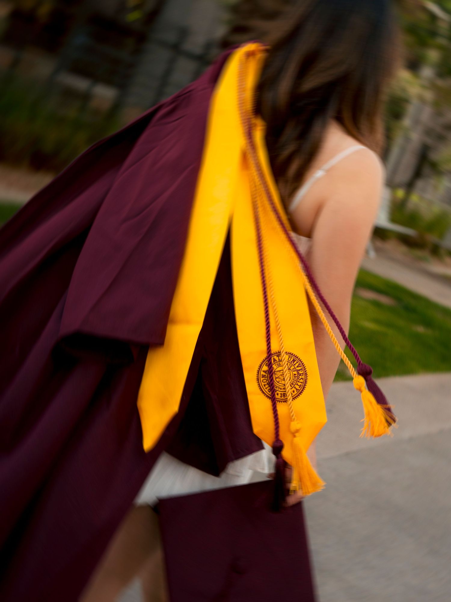 Close-up of maroon graduation gown with gold ASU tassel and stole draped over shoulder.