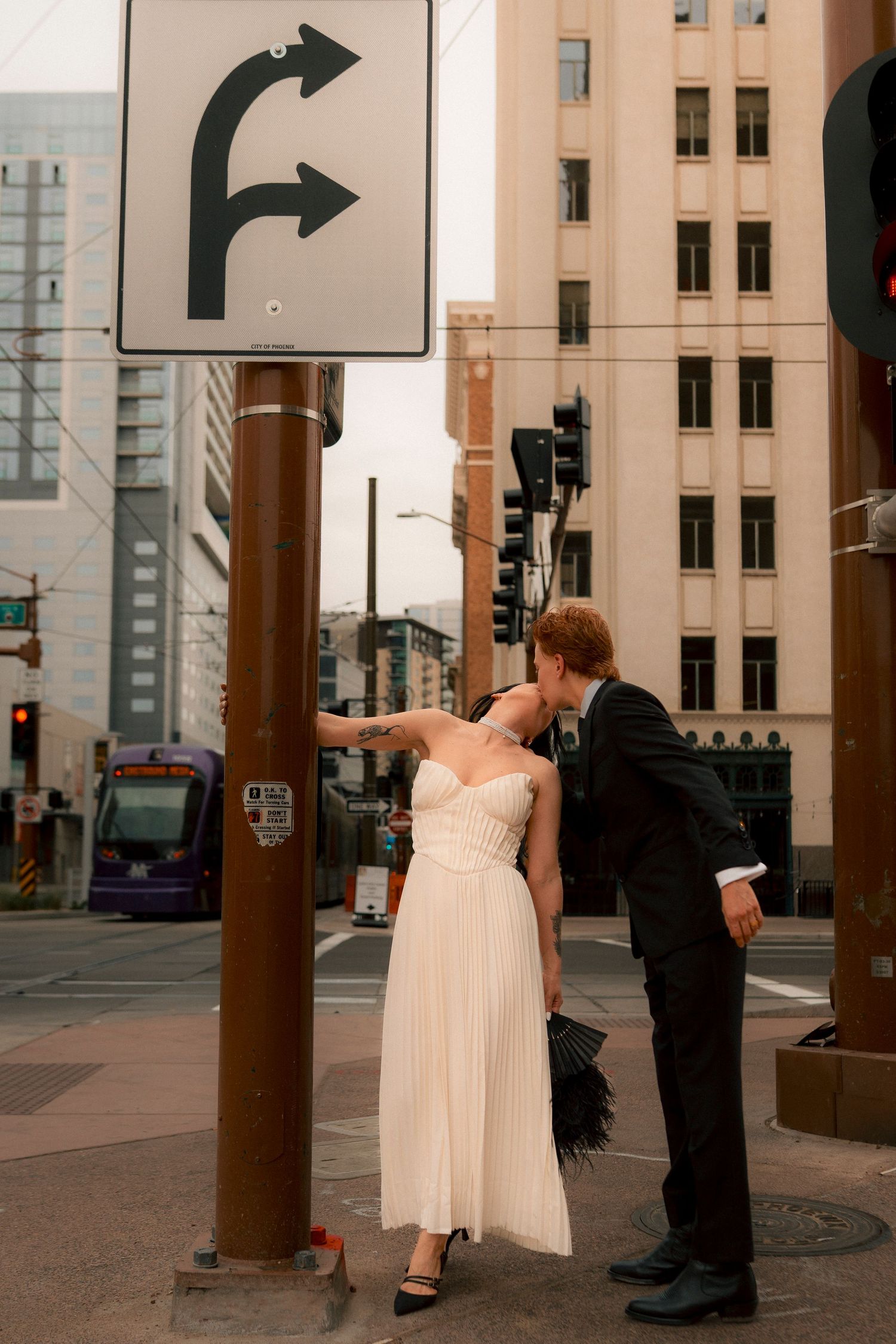 Newlywed couple shares a kiss beside a street sign in downtown Phoenix.