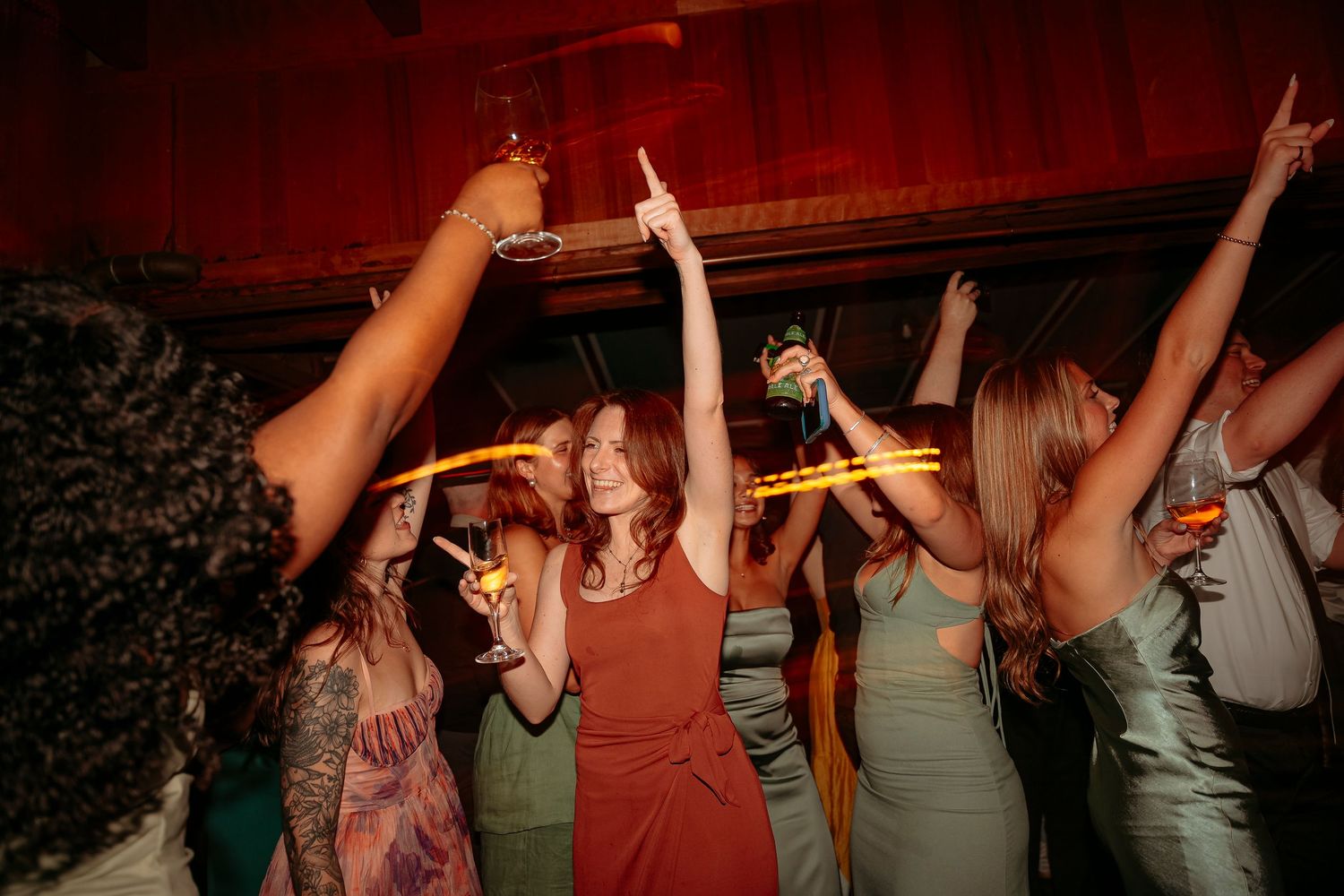 Guests dancing and celebrating with glow sticks at a lively wedding reception party.