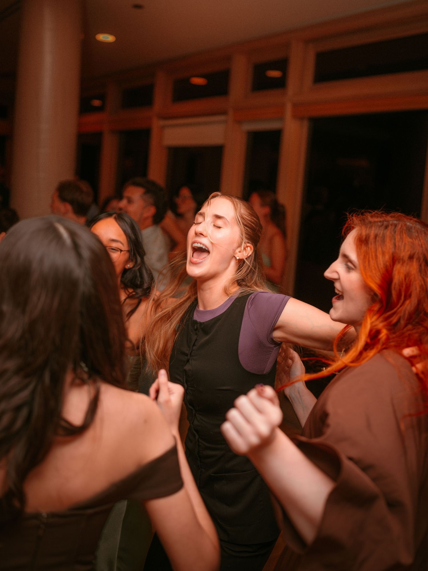 Women dancing and laughing joyfully at an indoor party event.