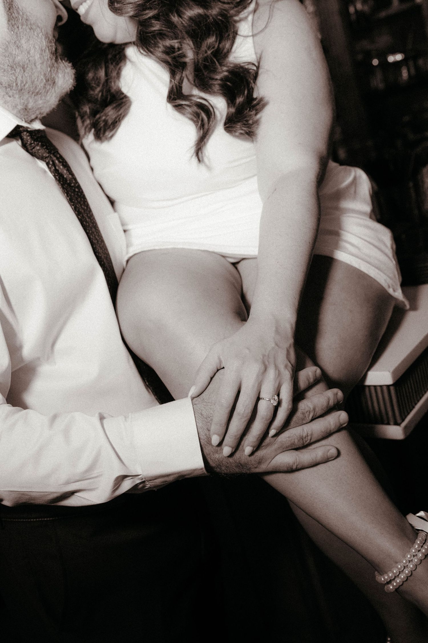 Black and white photo of a couple sharing an intimate moment, with a wedding ring visible on the woman's hand.