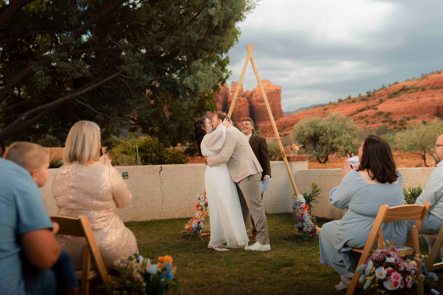 Couple sharing their first kiss at an outdoor wedding ceremony with stunning red rock formations backdrop.
