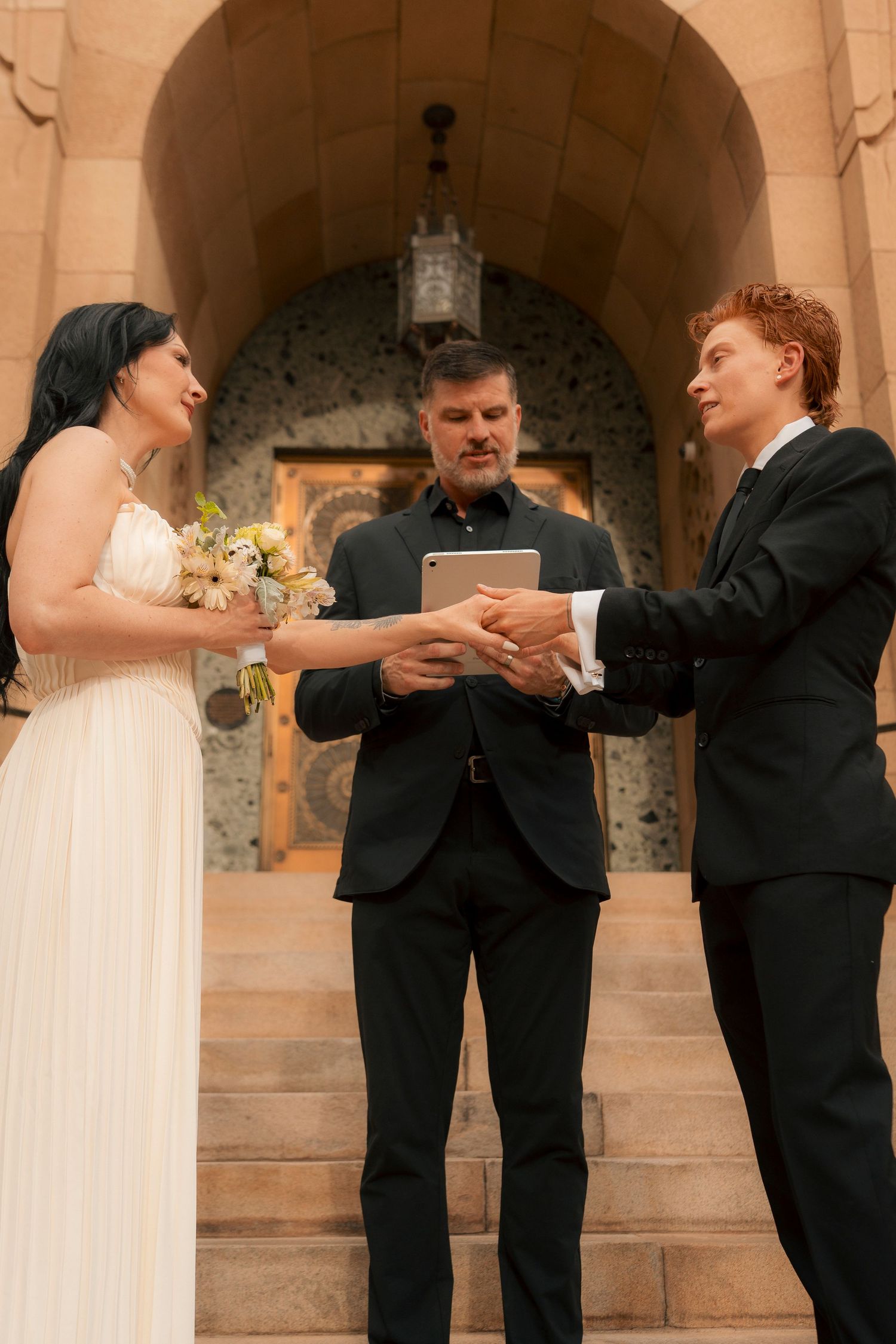 Bride and groom exchange vows with officiant on stone steps of Phoenix City Hall.