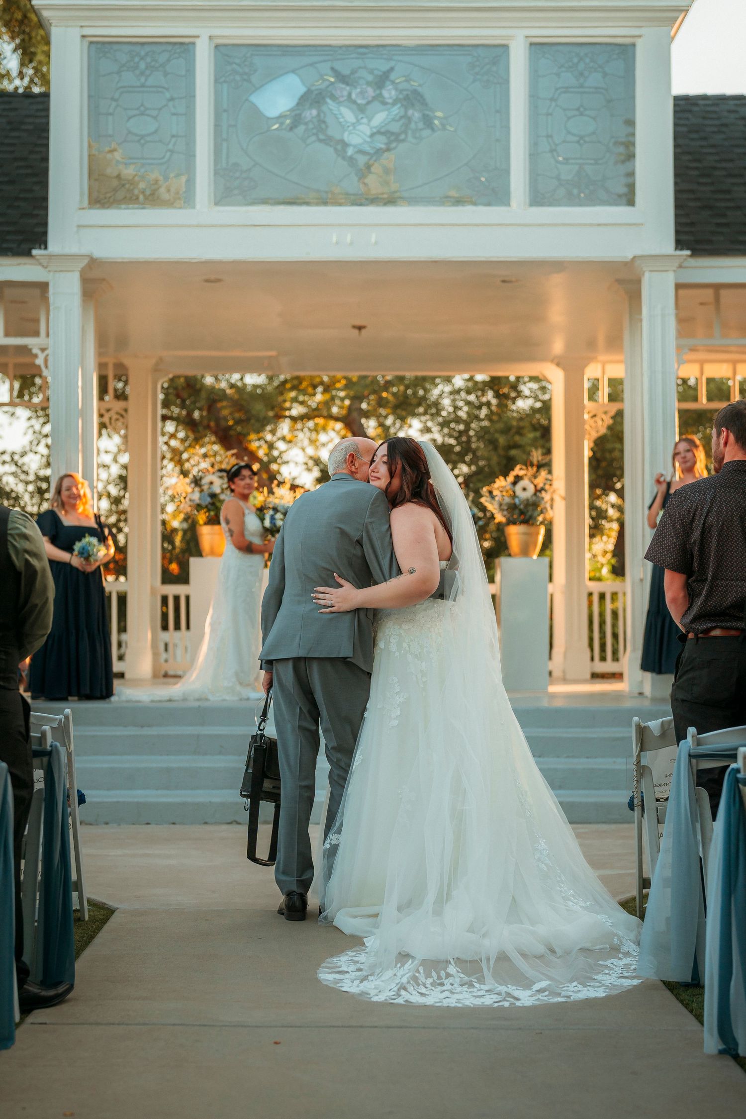Bride and groom share a romantic first kiss walking down the aisle at a white gazebo wedding ceremony.