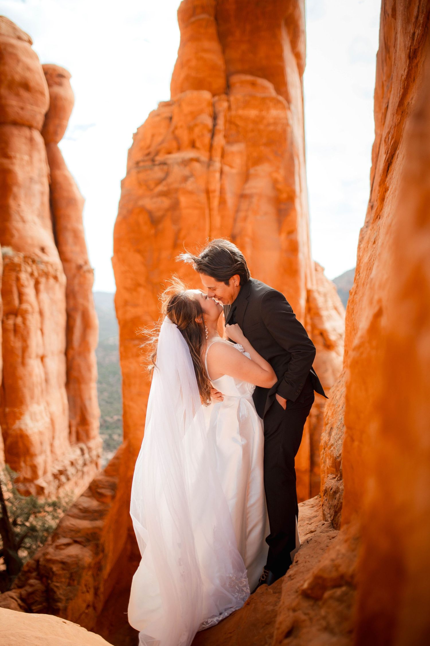 Bride and groom sharing a romantic kiss among towering red rock formations in Sedona, Arizona.