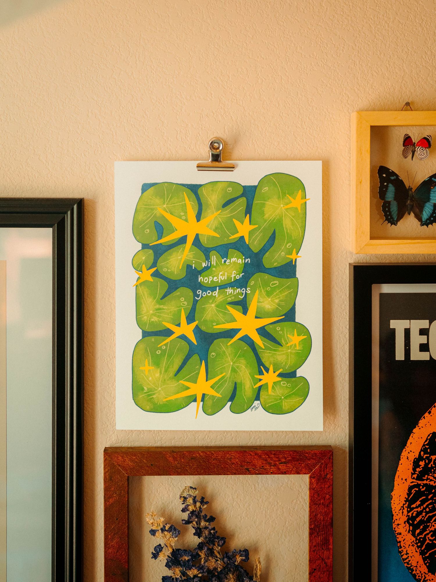 Colorful art print with green leaves and yellow starfish reading remain hopeful for good things on wall.