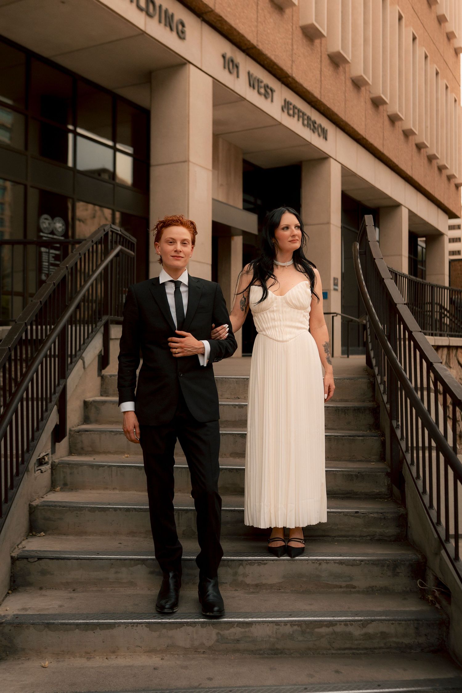 Elegant newlyweds descend stairs arm in arm outside 101 West Jefferson Court Building.