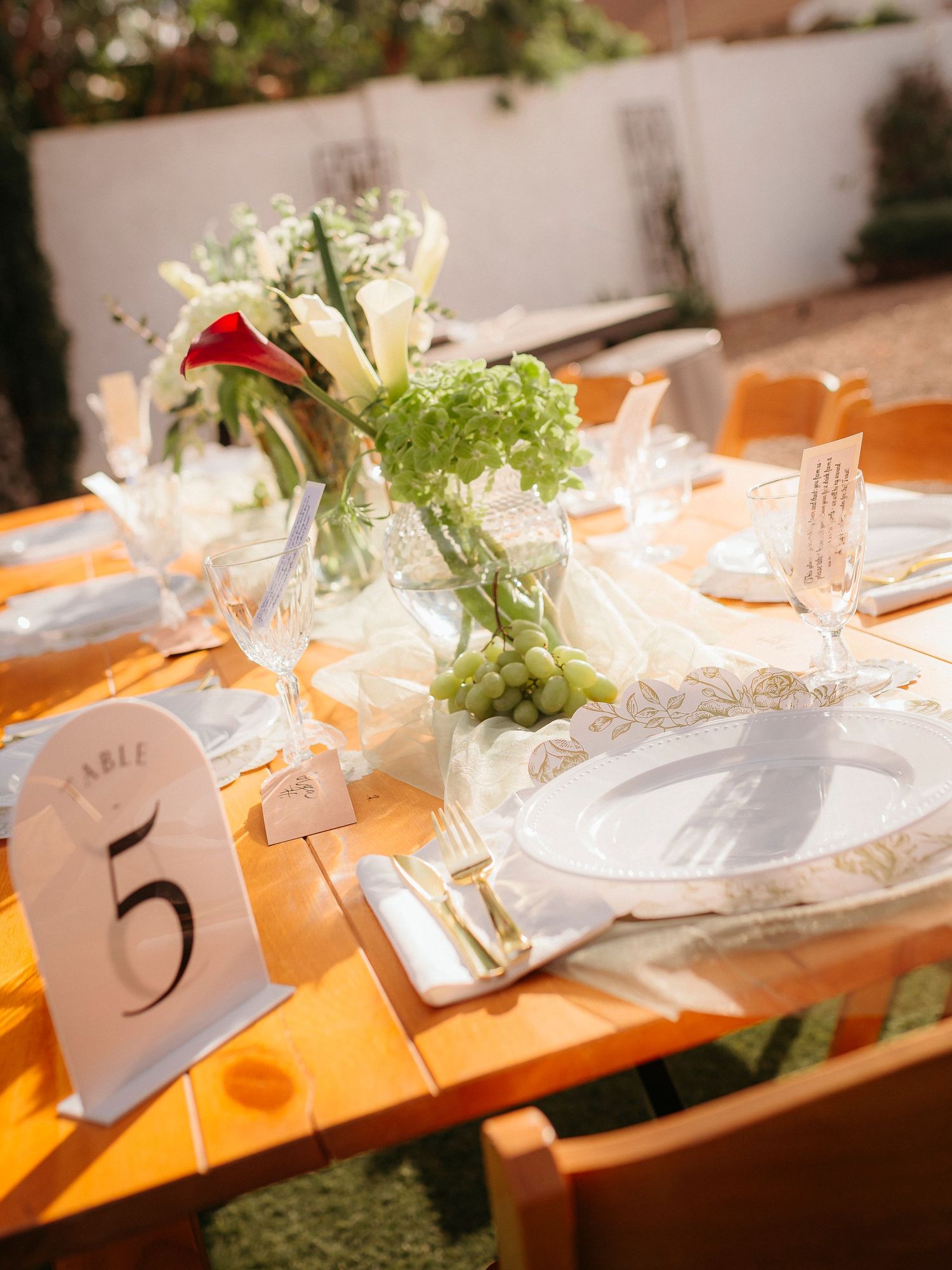 Elegant outdoor wedding table setting with floral centerpiece and Table 5 number card.