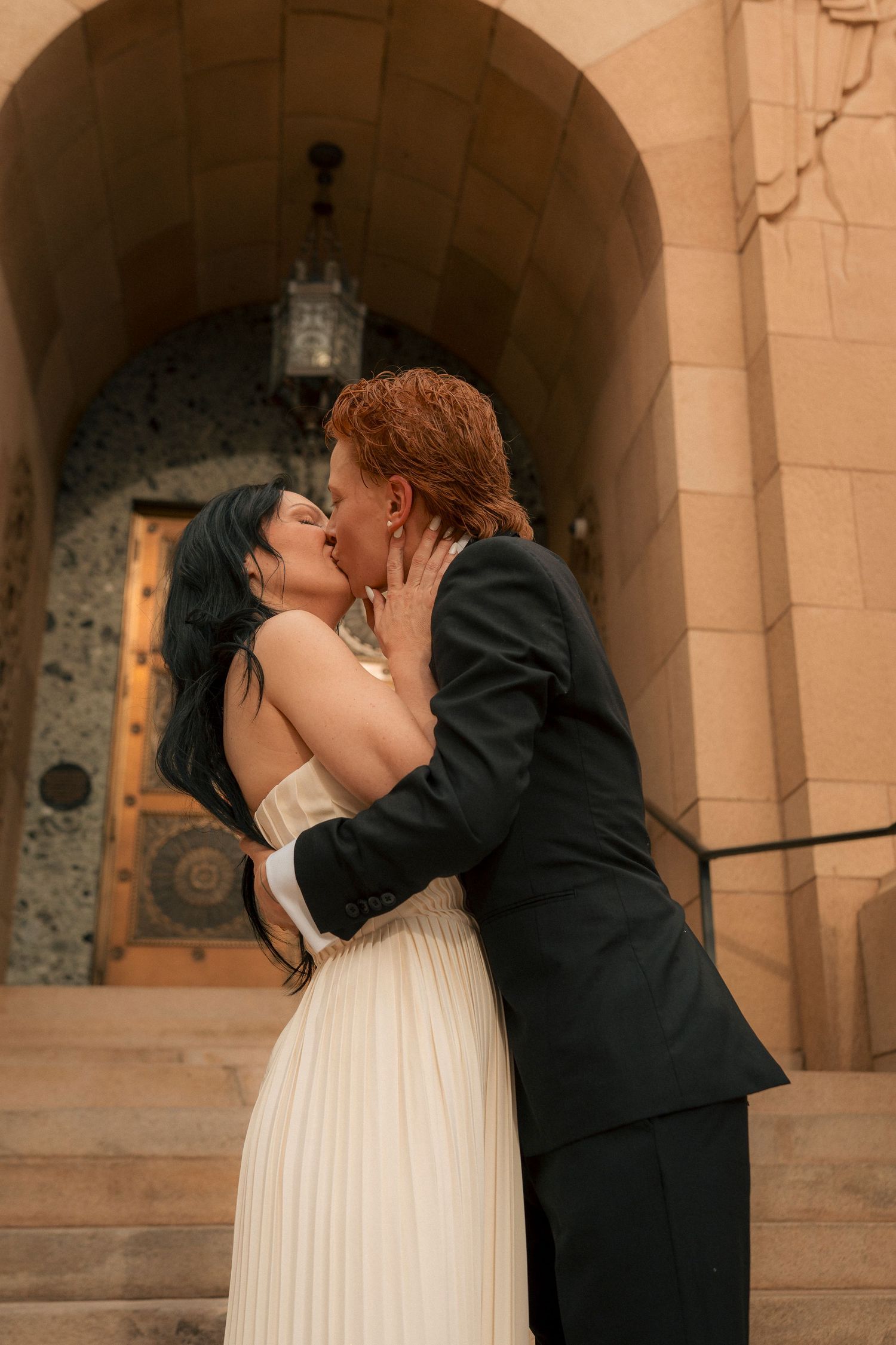 Newlywed couple shares first kiss on steps of historic Phoenix City Hall building.