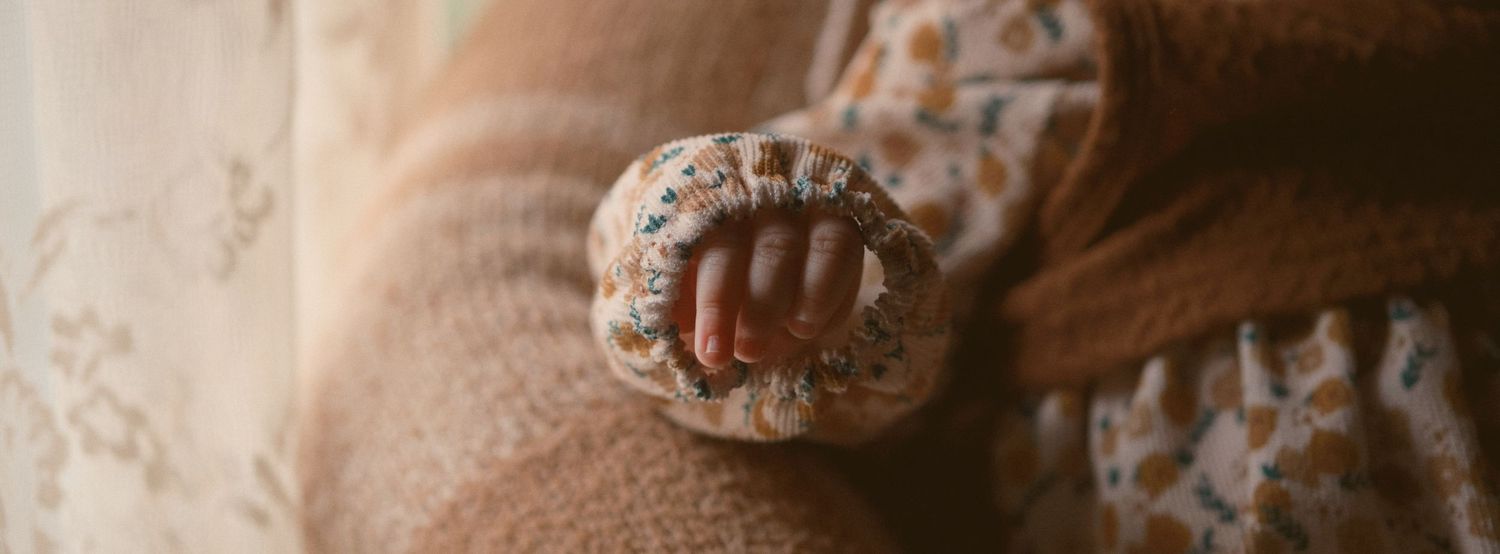 A photo of a baby's hand coming out of her shirt, taken in Snohomish County, Washington State. Photo by N&D Wedding Photography and Film