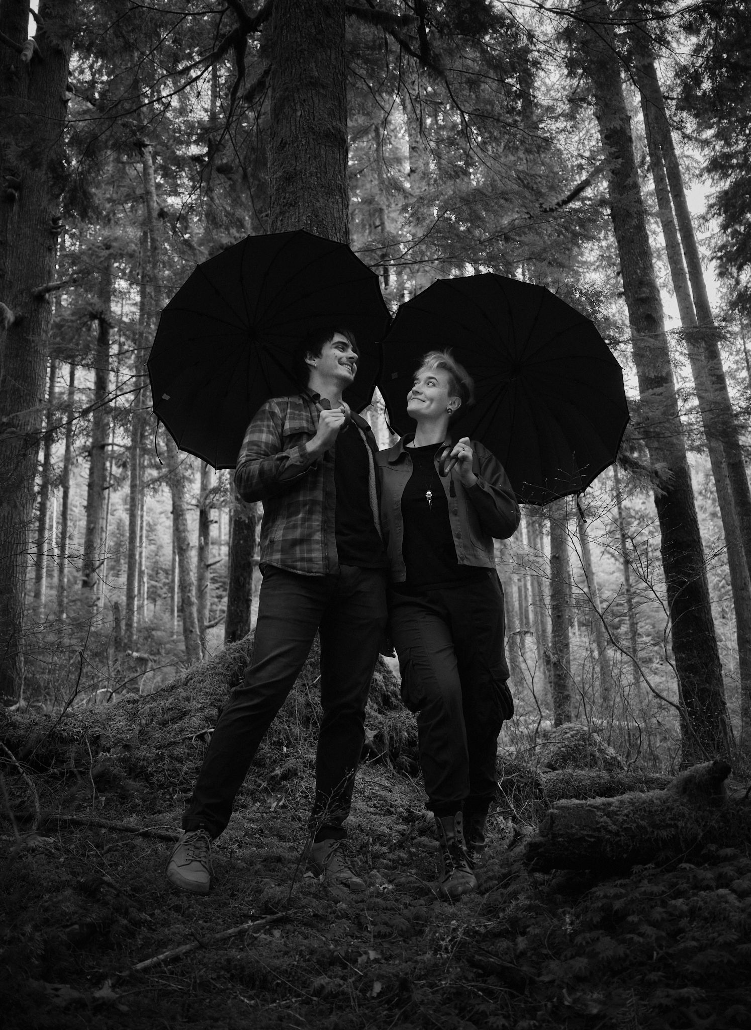 A portrait photo of a couple using their umbrellas in forest in Washington State. Photo by N&D Wedding Photography and Film