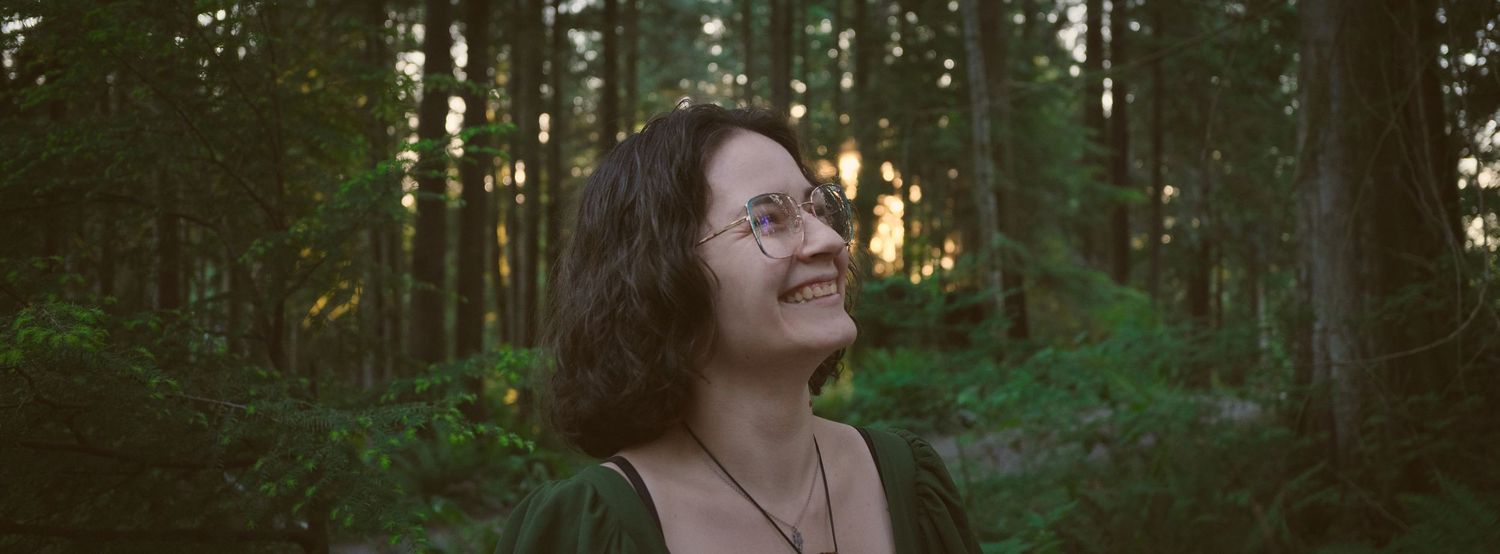 A photo of Foggé Crystal Company owner Miranda laughing in a Washington State forest. Photo by N&D Wedding Photography and Film