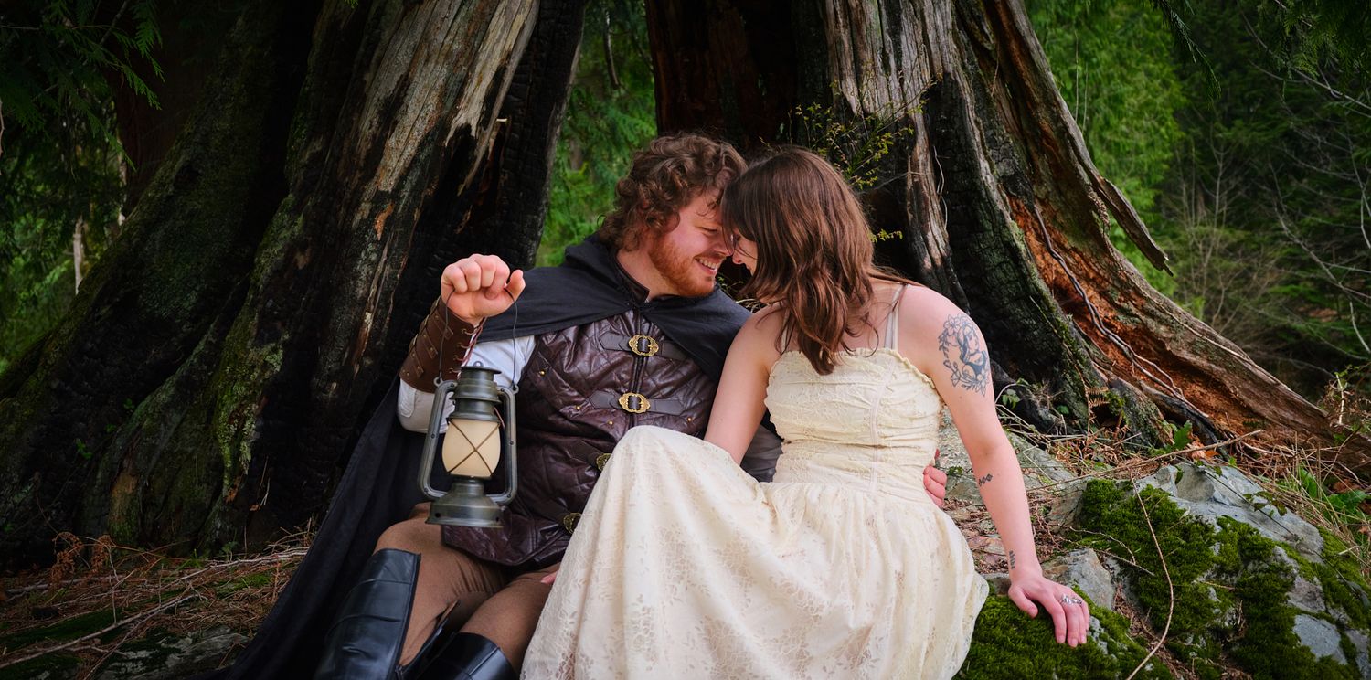 A couple sitting near a hollowed out tree with their heads touching, taken in WA, State. Photo by N&D Wedding Photography and Film