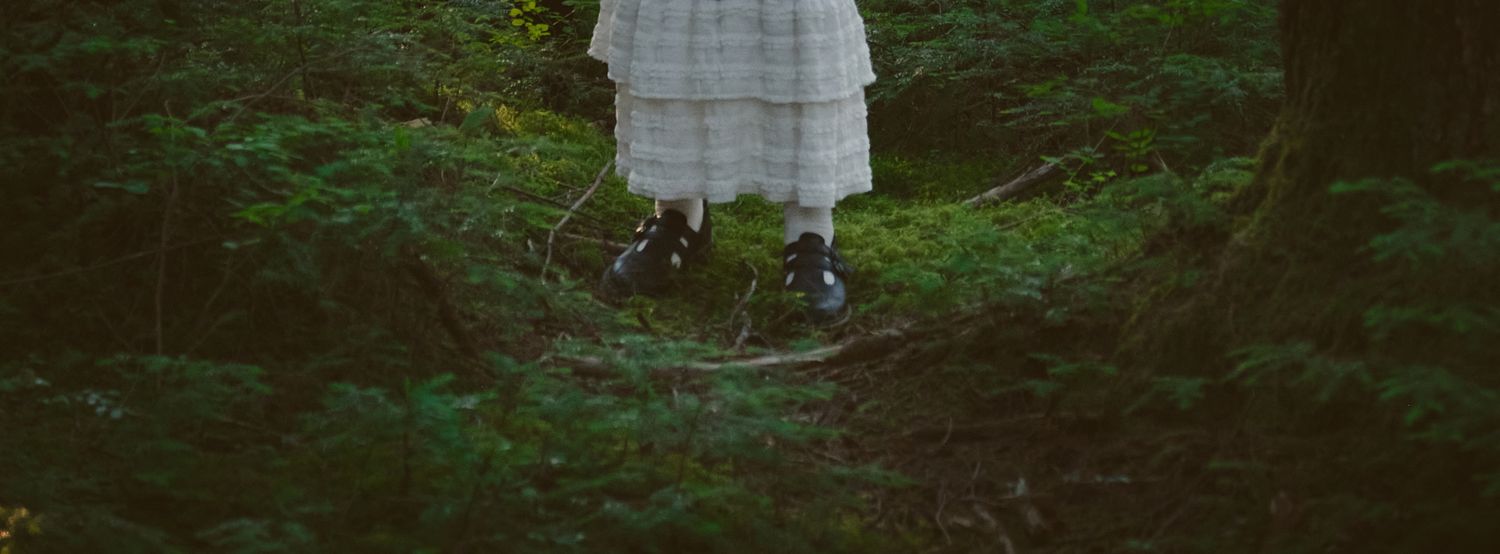 A photo of a girls shoes, she is standing on a forest floor in Washington state. Photo by N&D Wedding Photography and Film