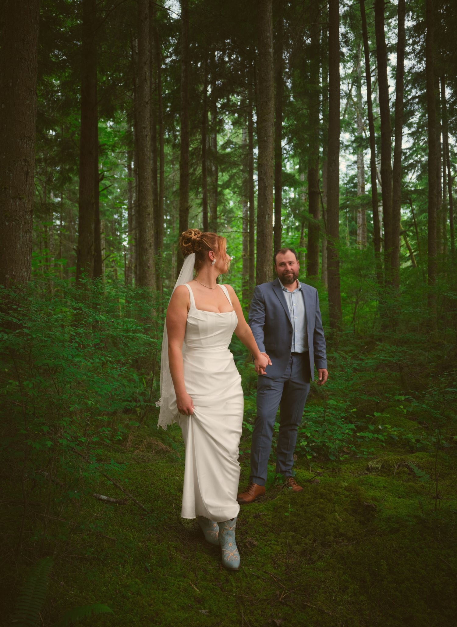 A bride leading her new husband through the woods in a Washington State forest. Photo by N&D Wedding Photography and Film